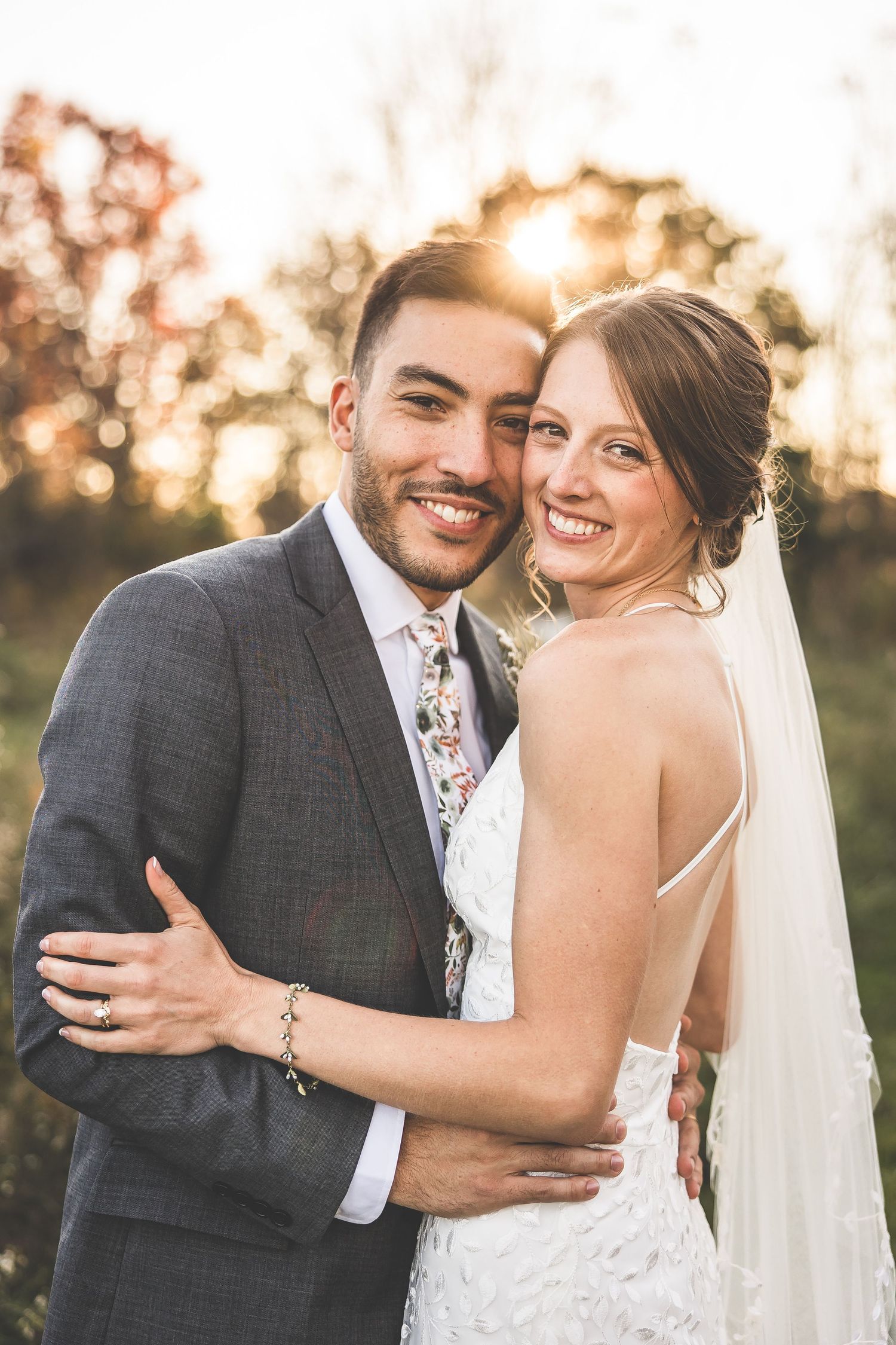 Newlyweds share joyful laughter during sunset portraits in an outdoor setting.