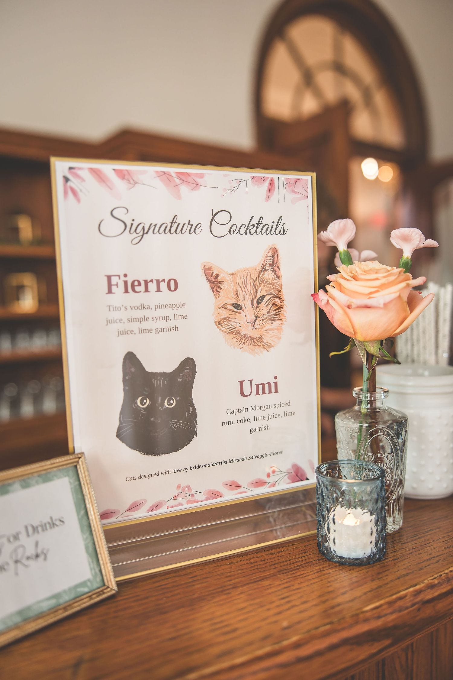 Custom cocktail menu cards with cat illustrations and floral designs on wooden table.