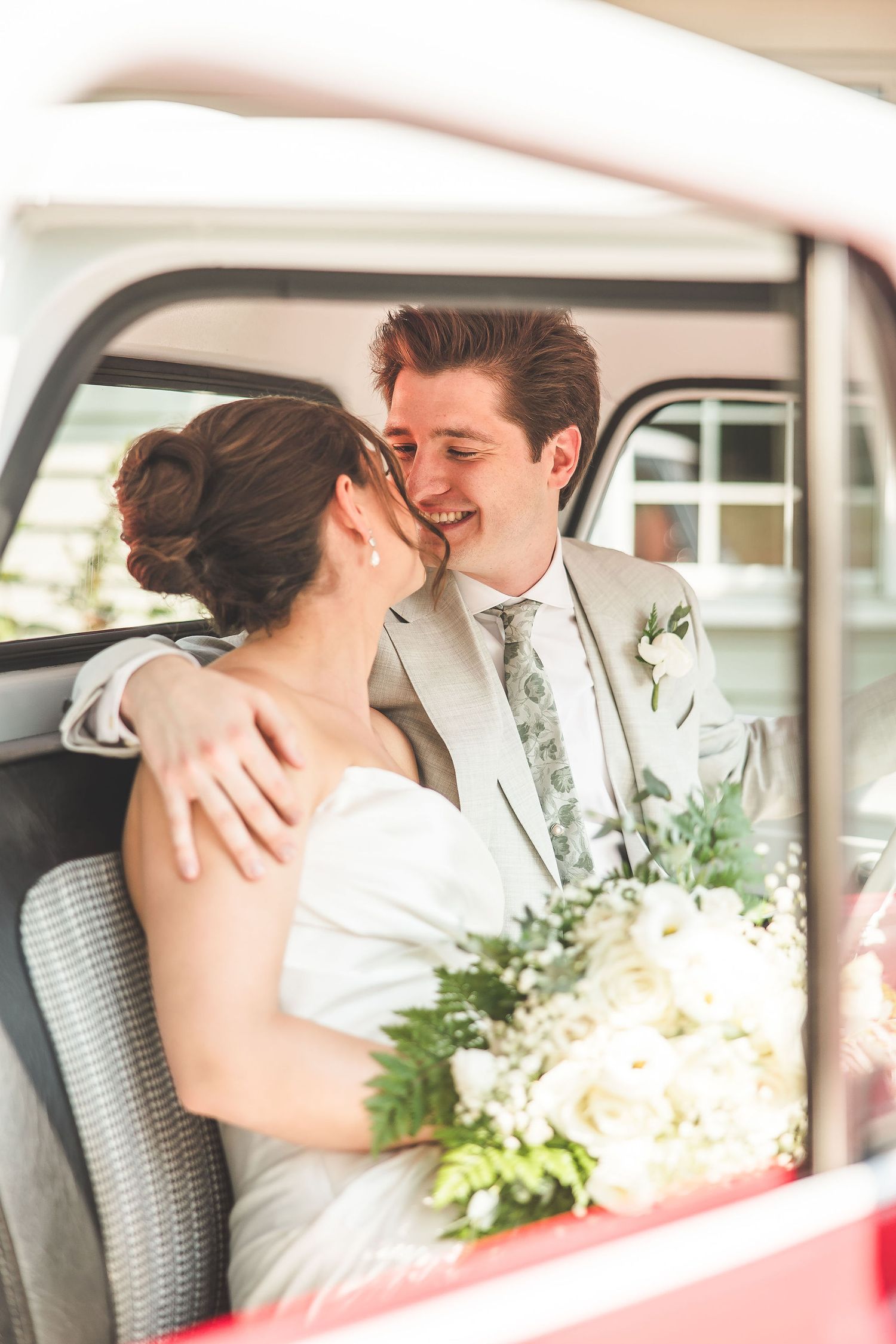 Intimate wedding moments captured through car windows with white floral bouquet visible.