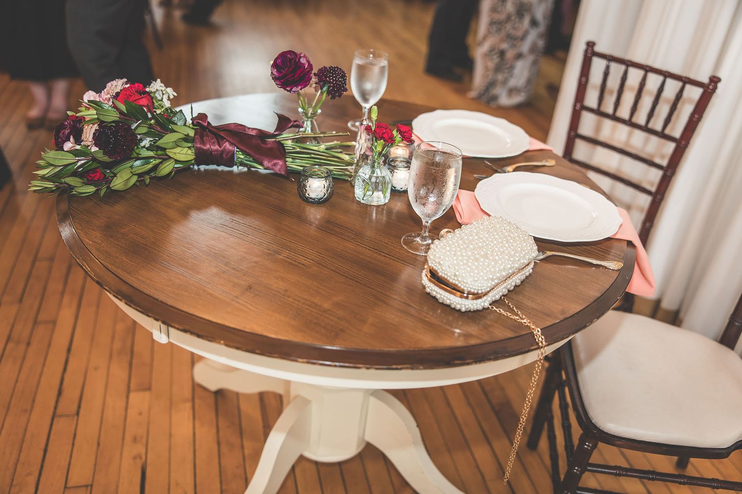 Wedding reception tables decorated with wooden chairs and floral centerpieces.