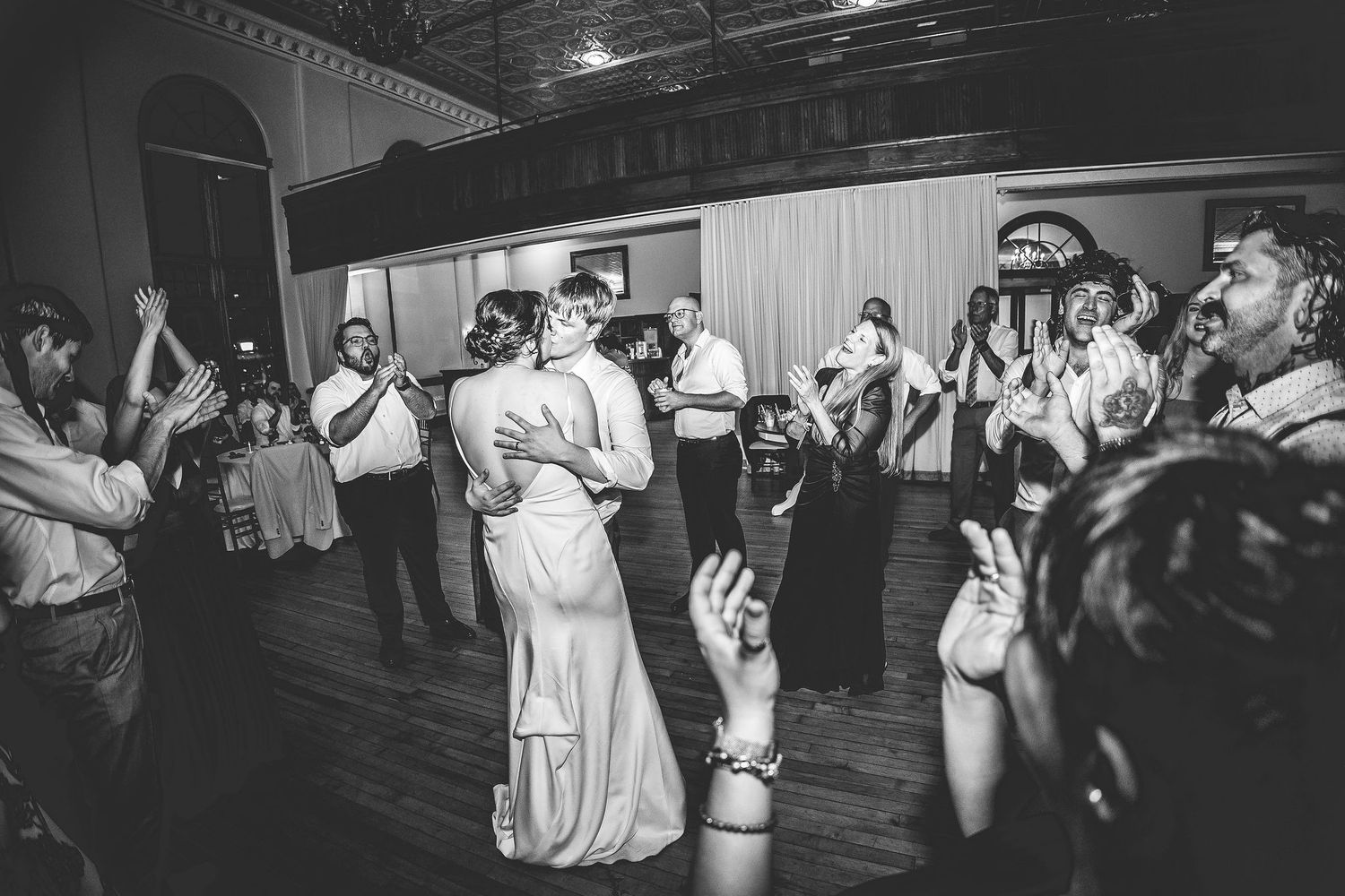 Black and white photo of wedding guests dancing and celebrating during an energetic reception.