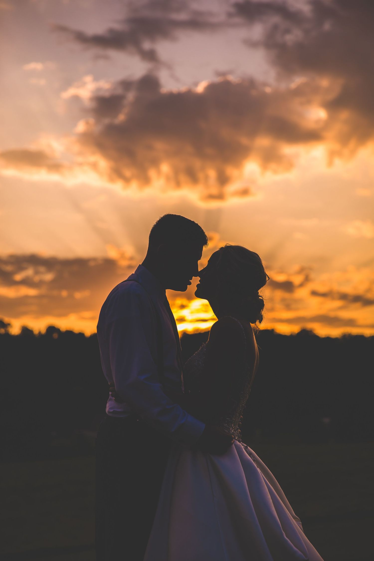 Silhouette of a couple against a dramatic orange sunset sky.