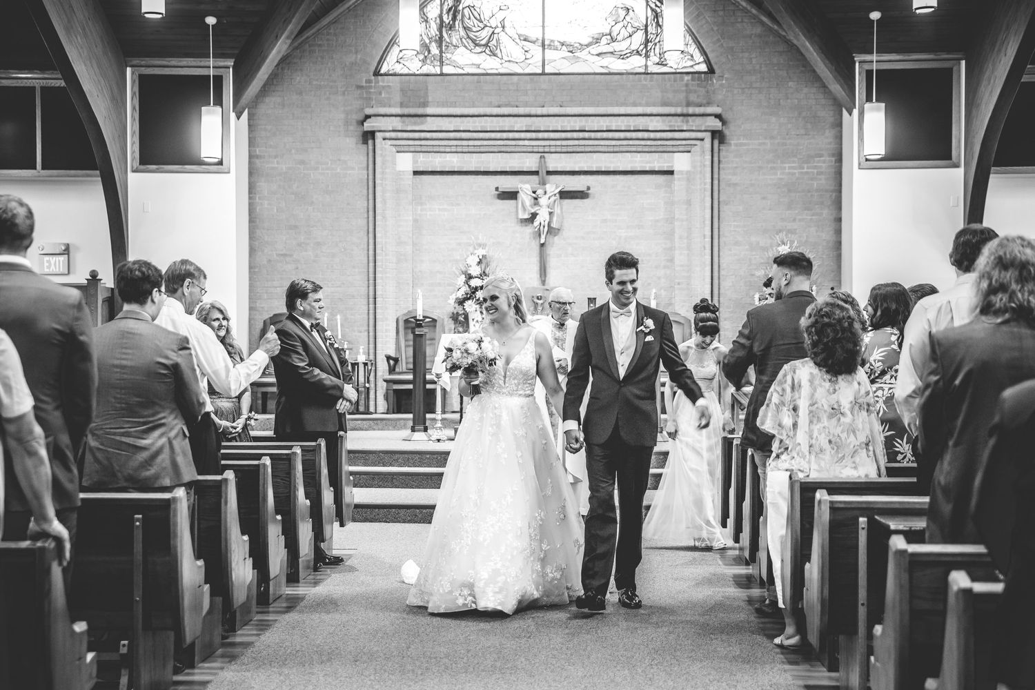Black and white photo of traditional church wedding ceremony with guests seated in pews.