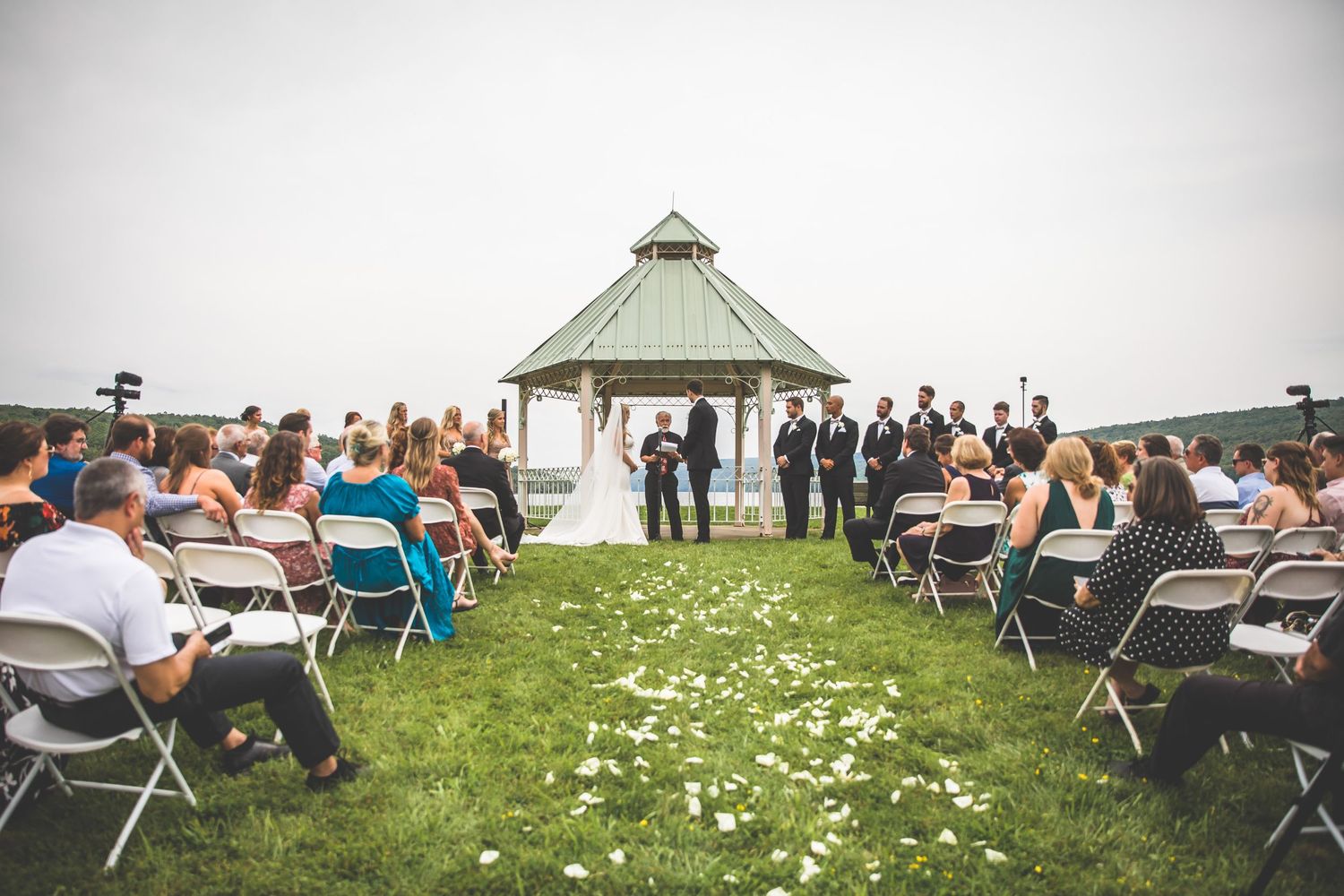 White folding chairs arranged on grassy lawn for outdoor wedding ceremony with gazebo.