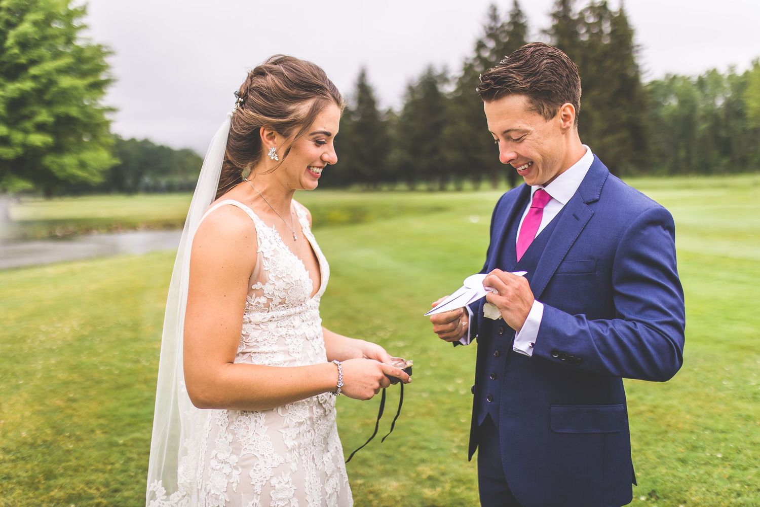 A couple exchanges heartfelt moments while reading personal vows during their outdoor ceremony.