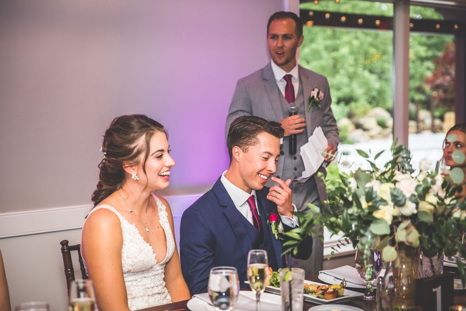 Wedding reception dining tables decorated with white floral arrangements and elegant place settings.