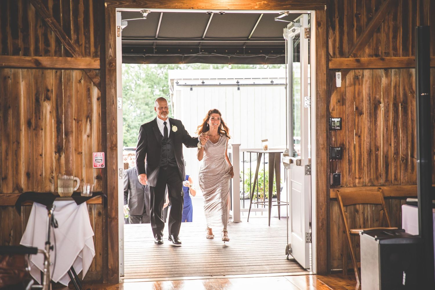 Wedding celebration entrance in rustic barn venue with wooden walls and natural lighting.