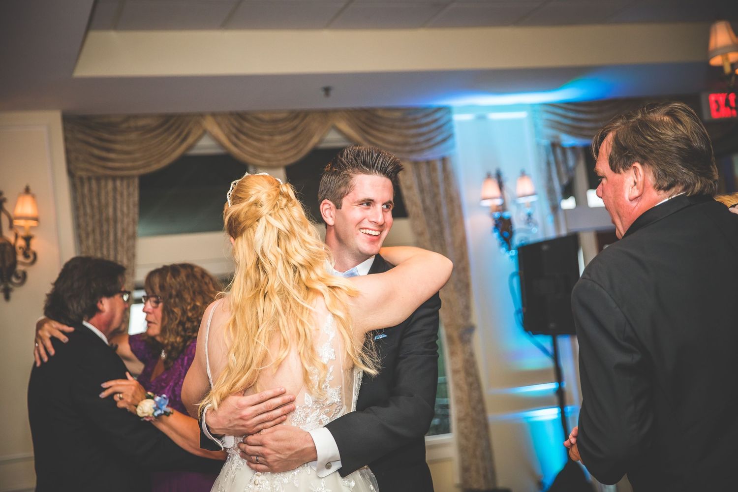 Wedding reception dance captured in warm lighting with decorative drapes in the background.