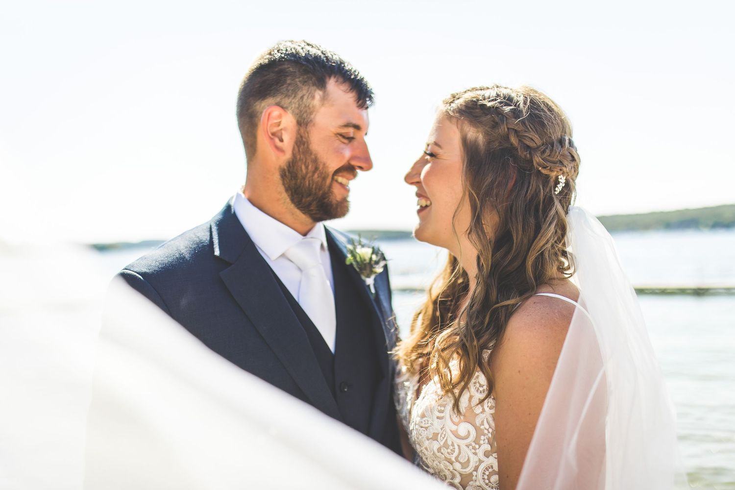 Romantic waterfront wedding portraits at sunset with soft natural lighting.