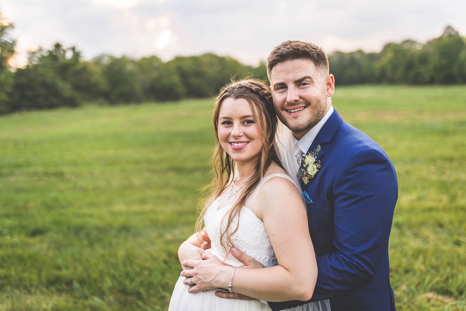 Wedding couple sharing intimate moments in a grassy field at sunset.
