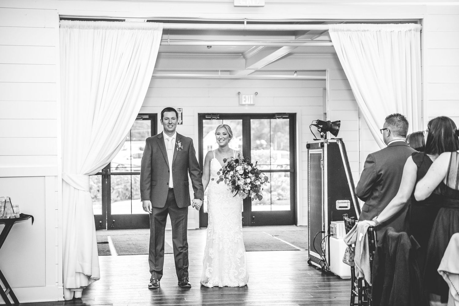 Black and white wedding ceremony moments captured in a bright indoor venue.