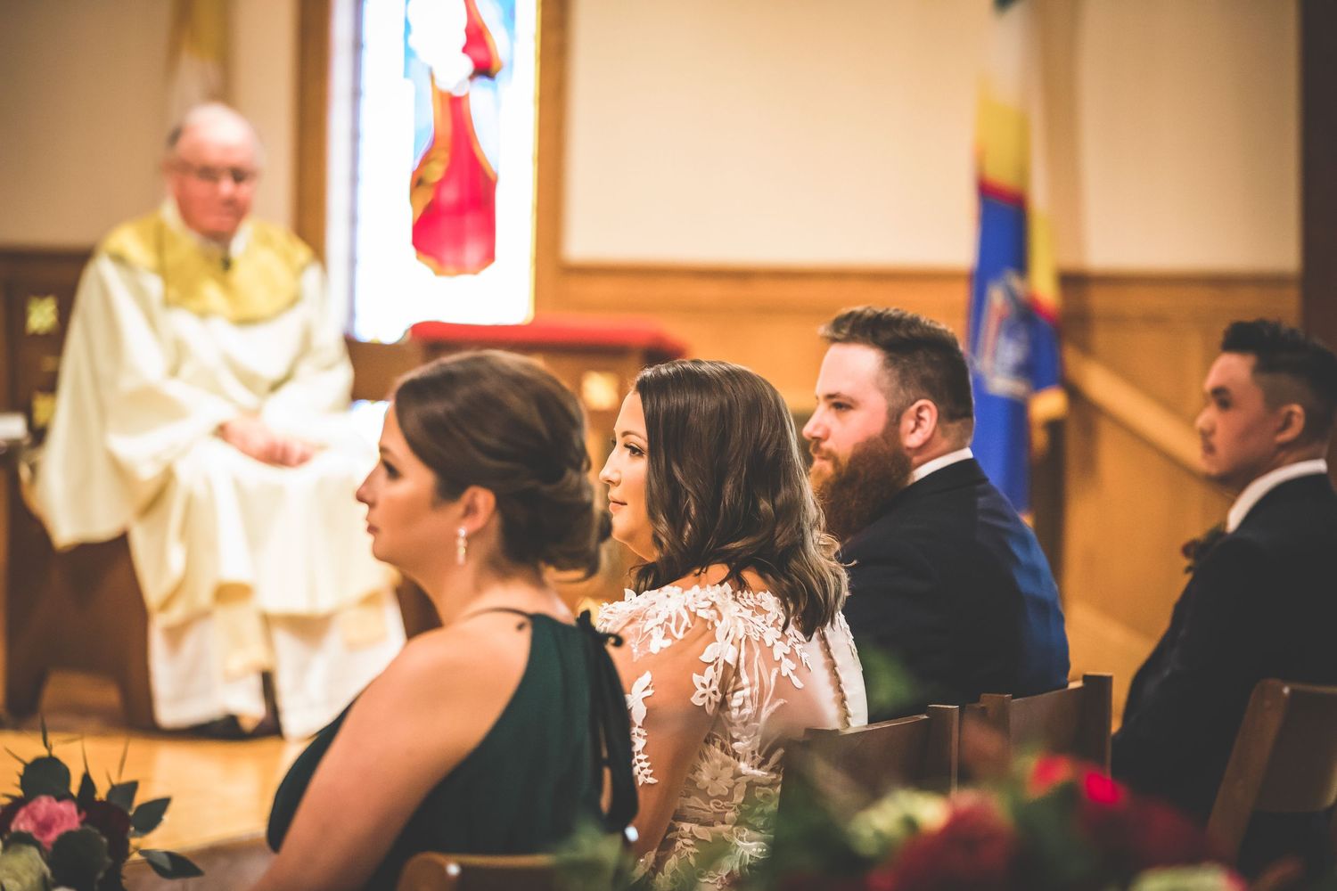 Church wedding ceremony with guests seated in wooden pews.