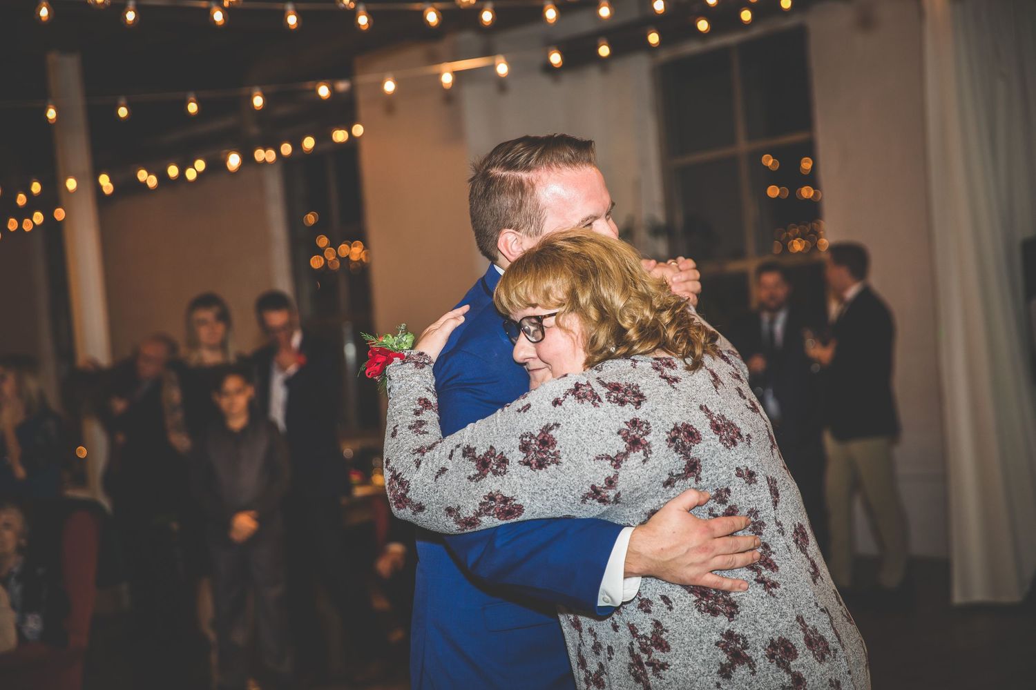 Couples dancing at wedding reception beneath warm string lights and elegant decor.