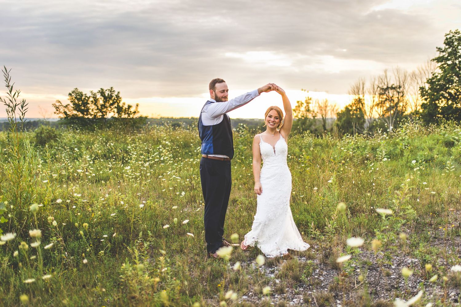 Wedding party walking through a scenic meadow at sunset.