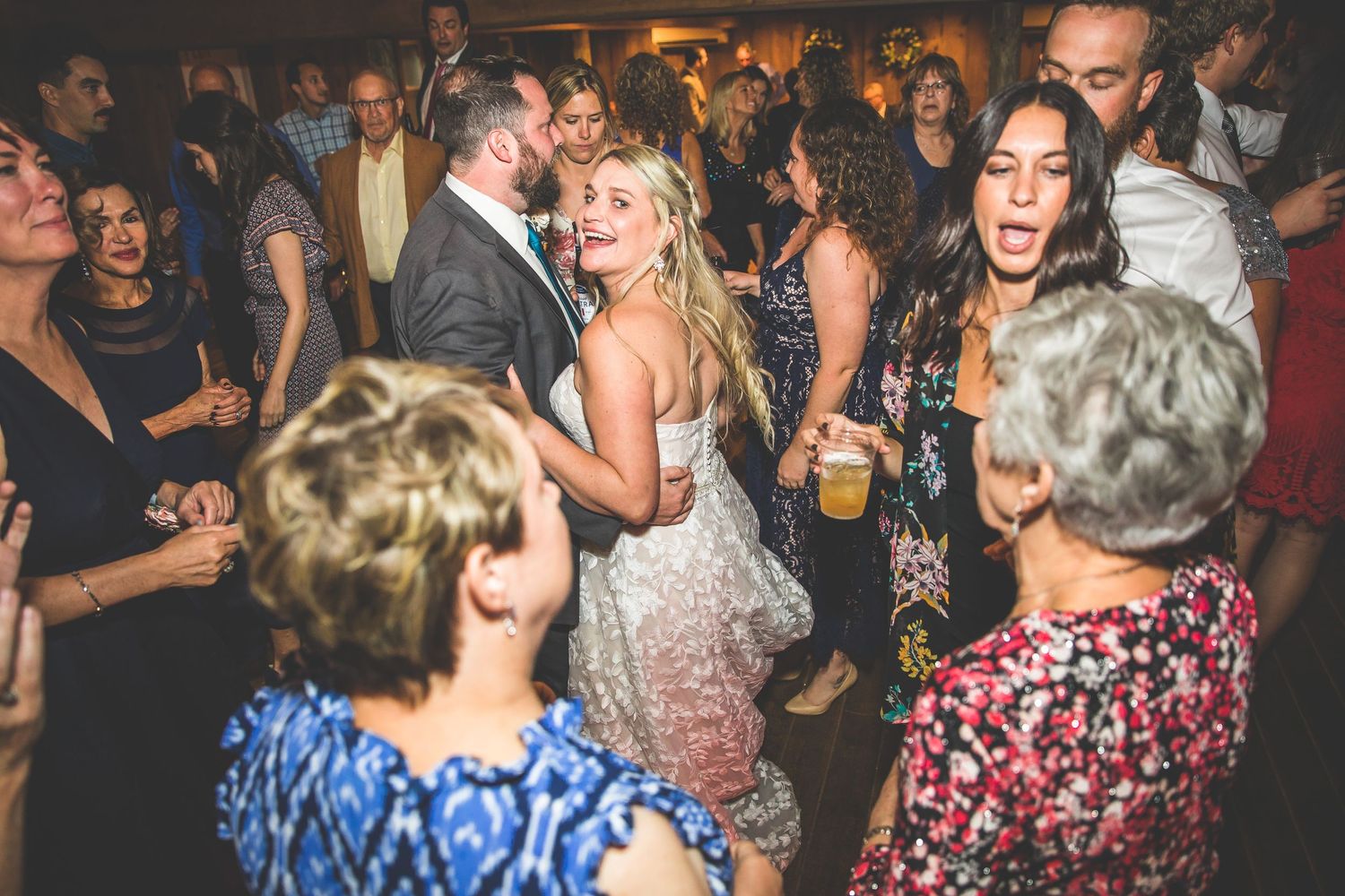Wedding guests dancing and celebrating on the dance floor at a lively reception.
