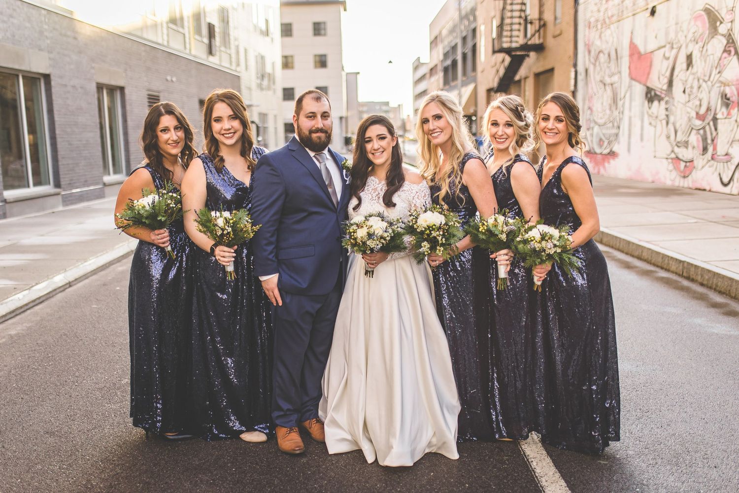 Bridal party with bridesmaids in navy dresses pose together outdoors.