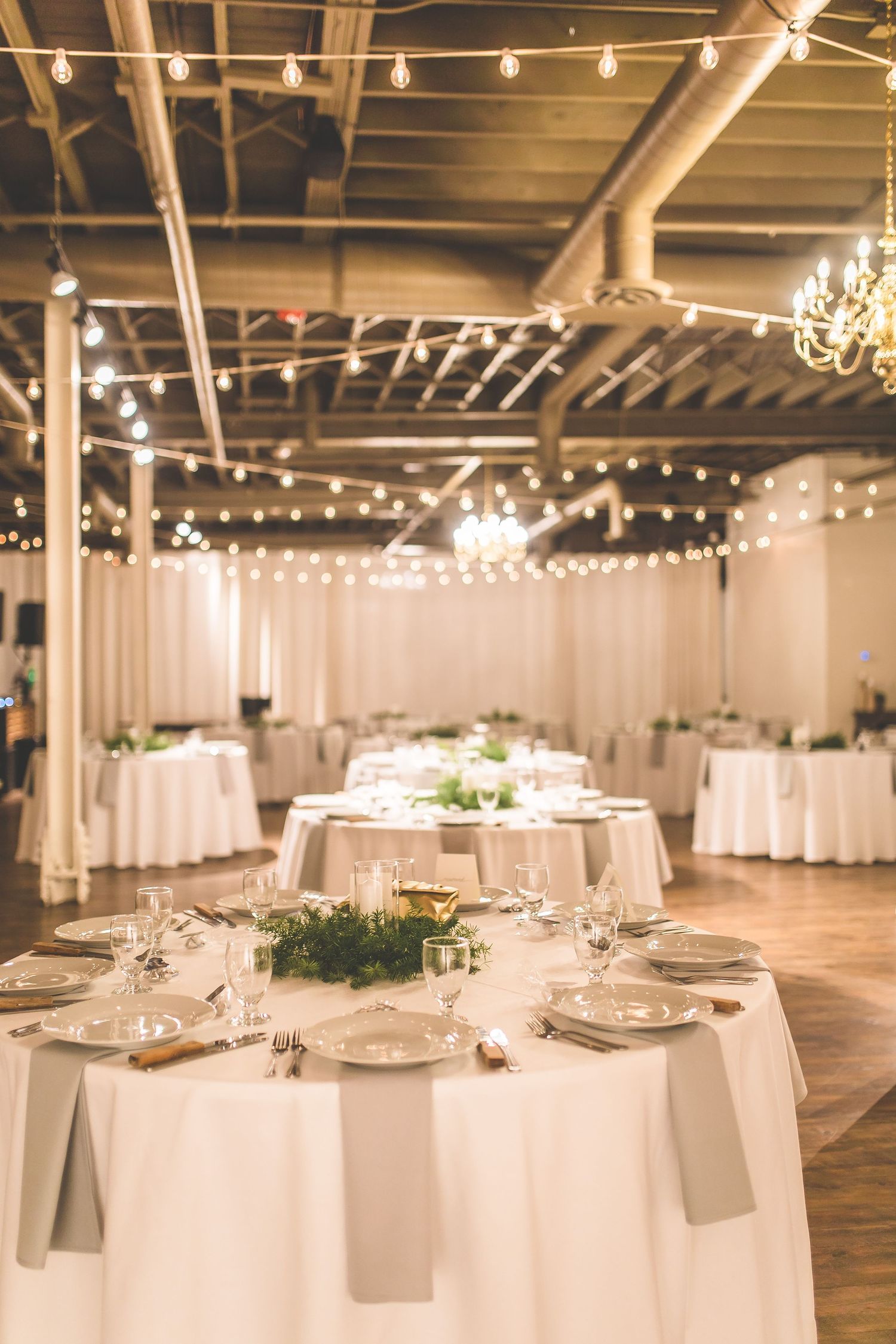 Wedding reception venue with white tablecloths and string lights creating romantic ambiance.