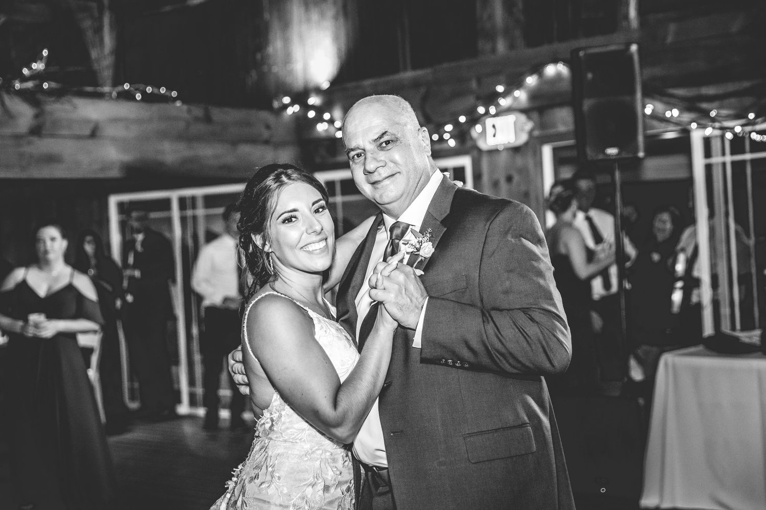 Black and white photo of wedding guests dancing and celebrating on the dance floor.