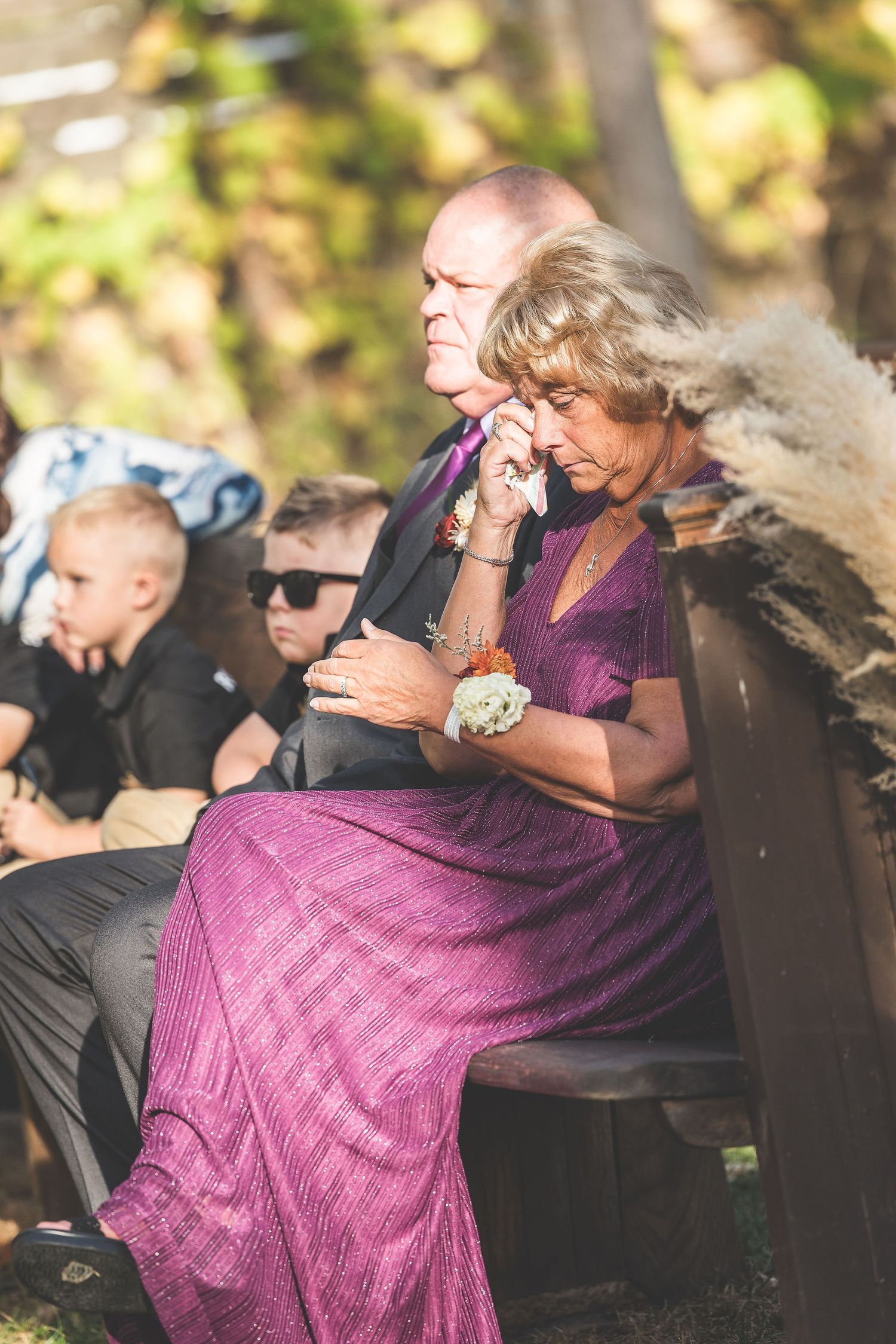 Emotional moment at outdoor wedding ceremony as attendees embrace during autumn gathering.