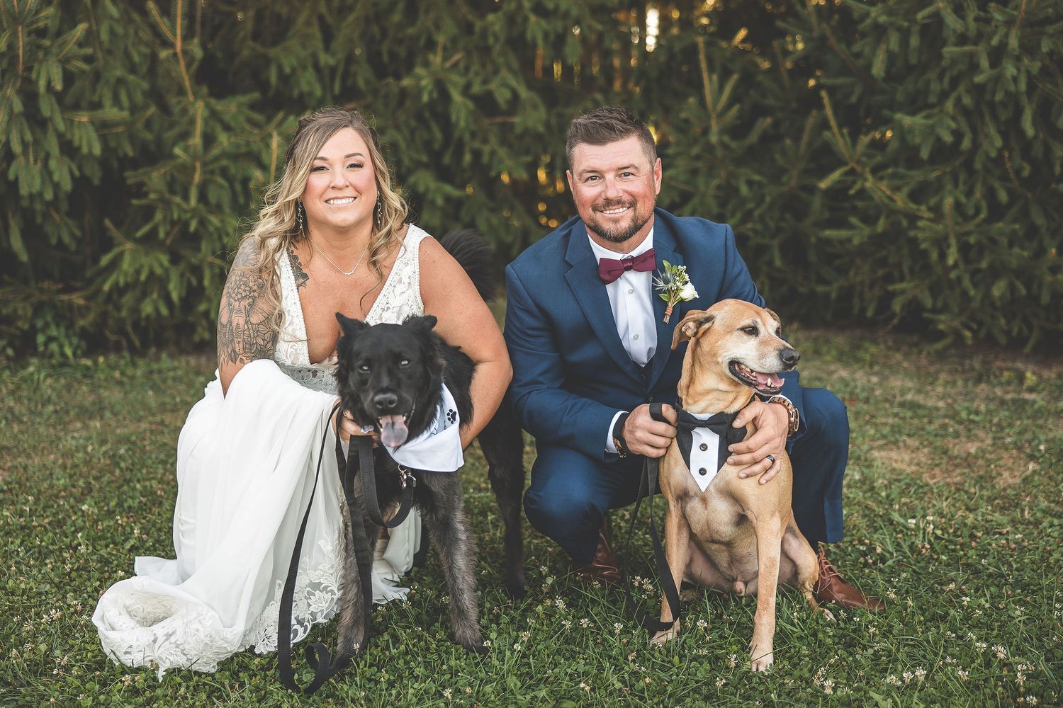Wedding couple sits on grass with their golden retriever dog in formal attire.