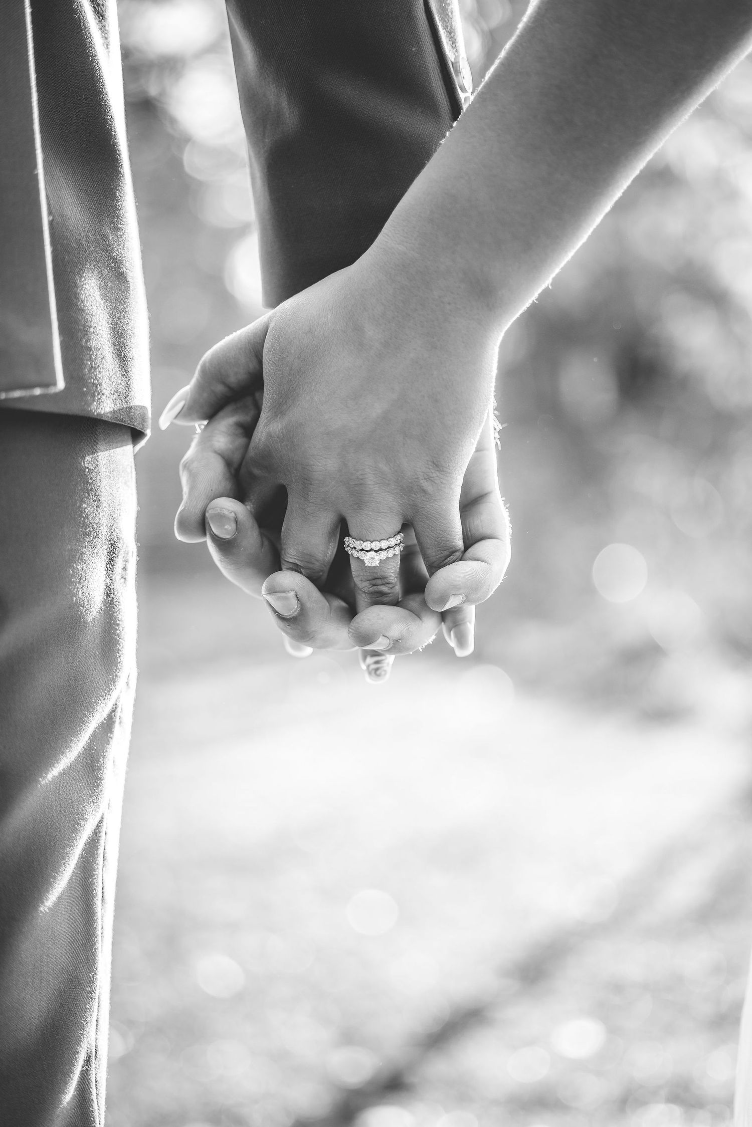 Black and white close-up of wedding rings and clasped hands showing intimate wedding details.