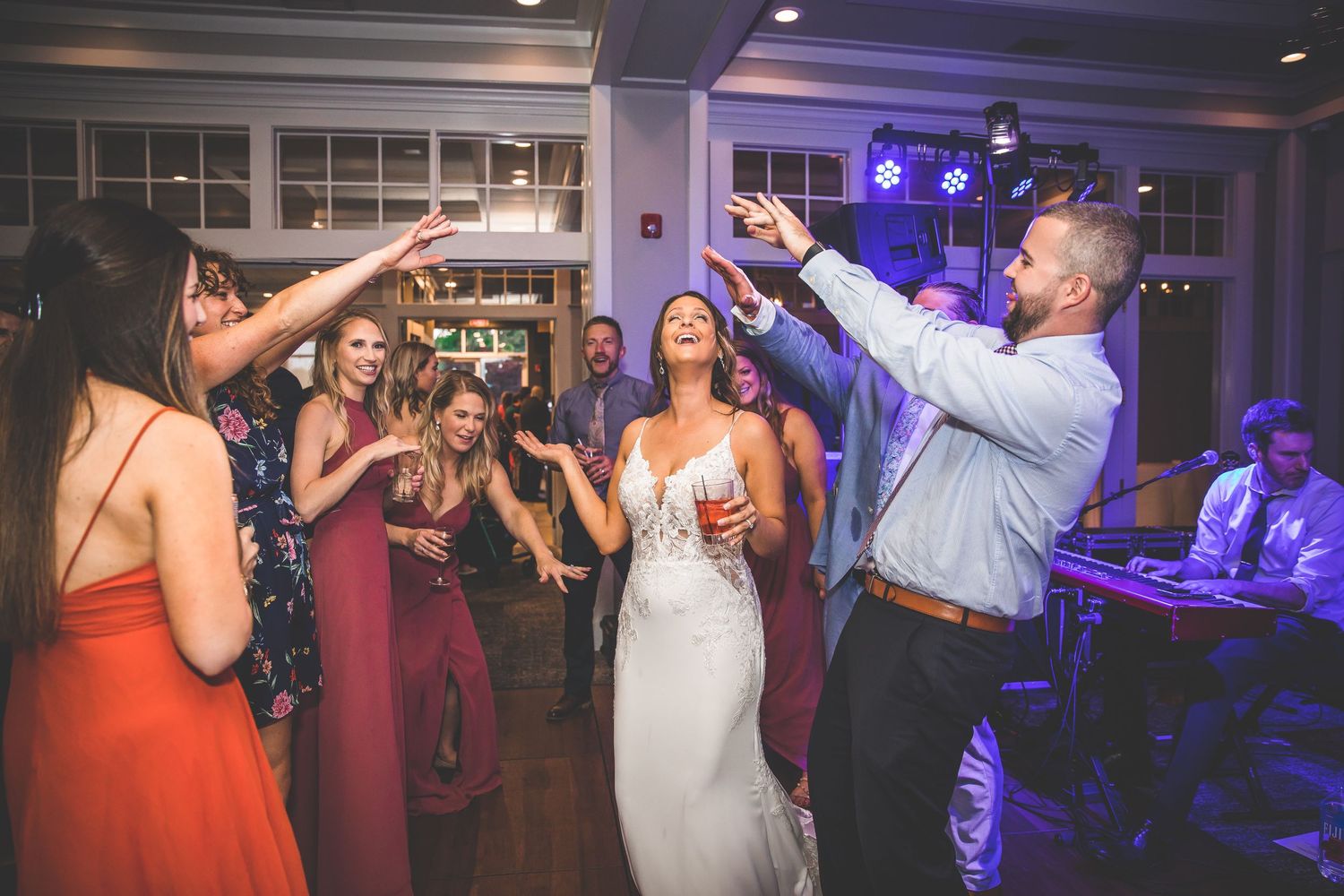 Wedding celebration with guests dancing under blue lighting in an elegant indoor venue.