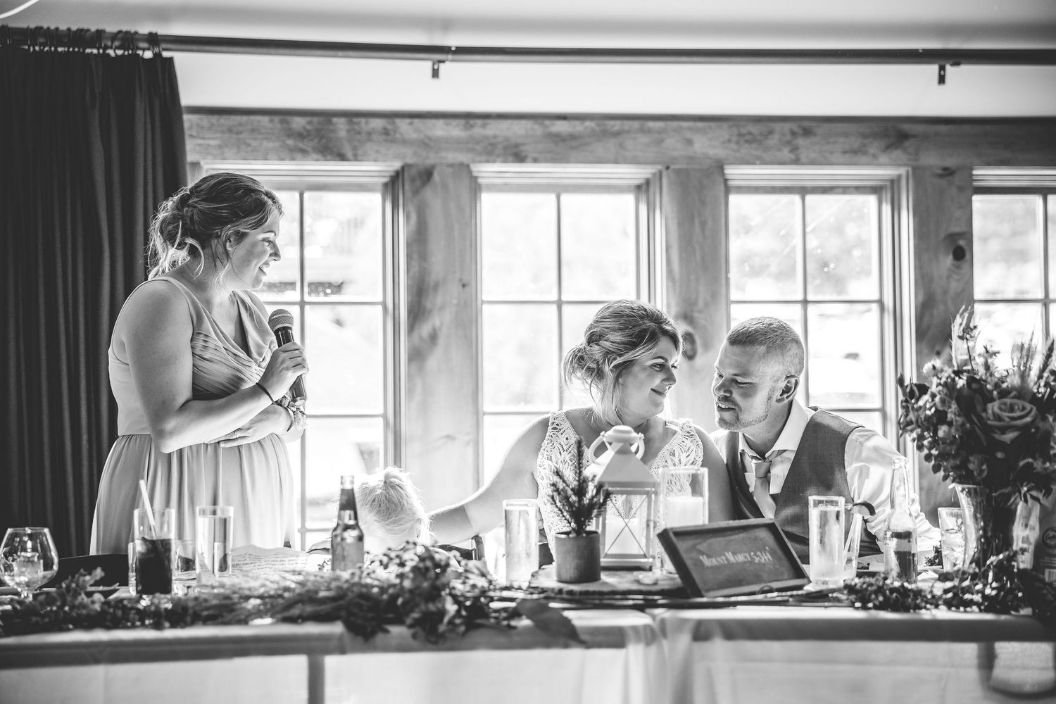 Panoramic black and white view of an elegant wedding reception venue with large windows.