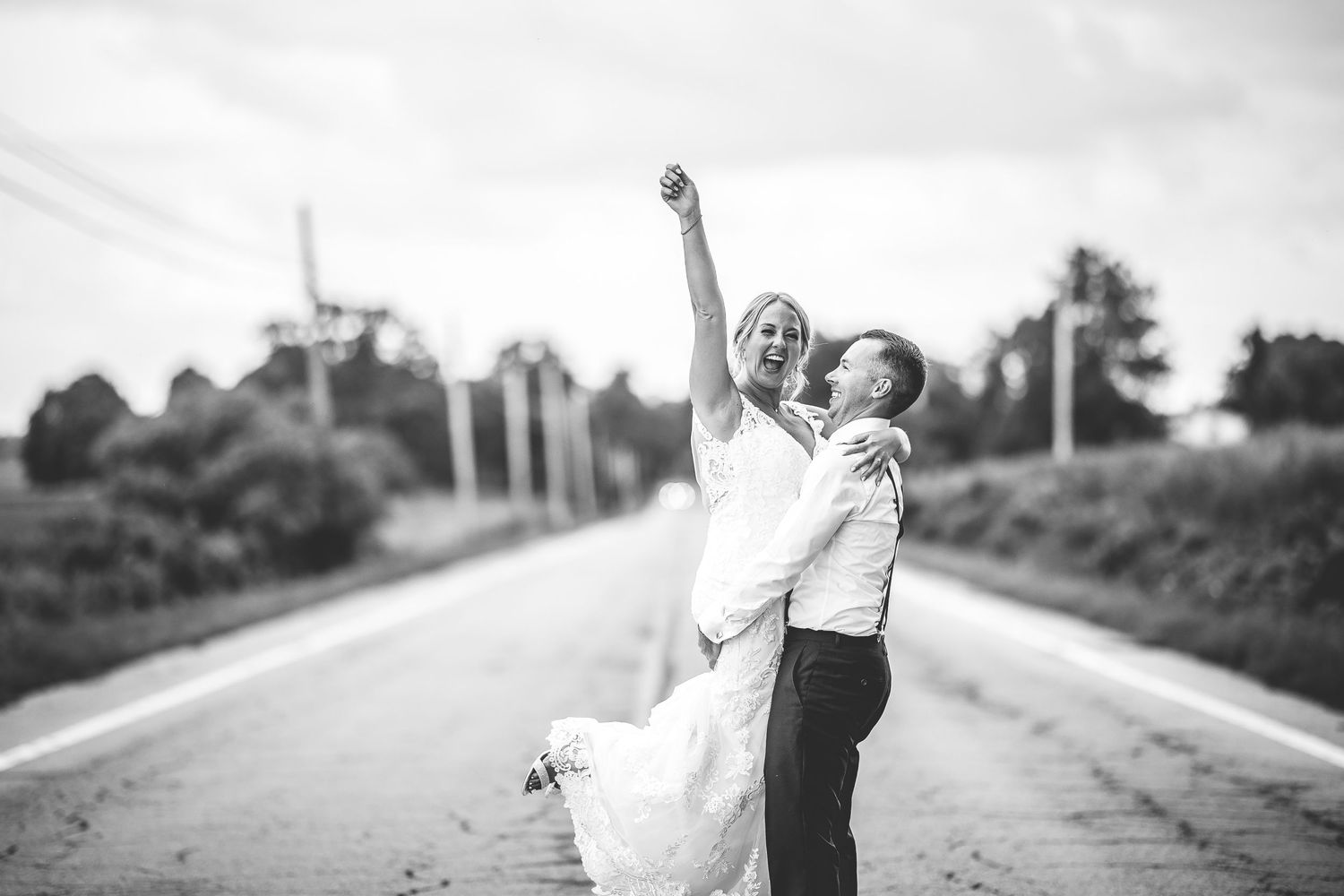 Black and white wedding photos showing romantic poses on a country road.