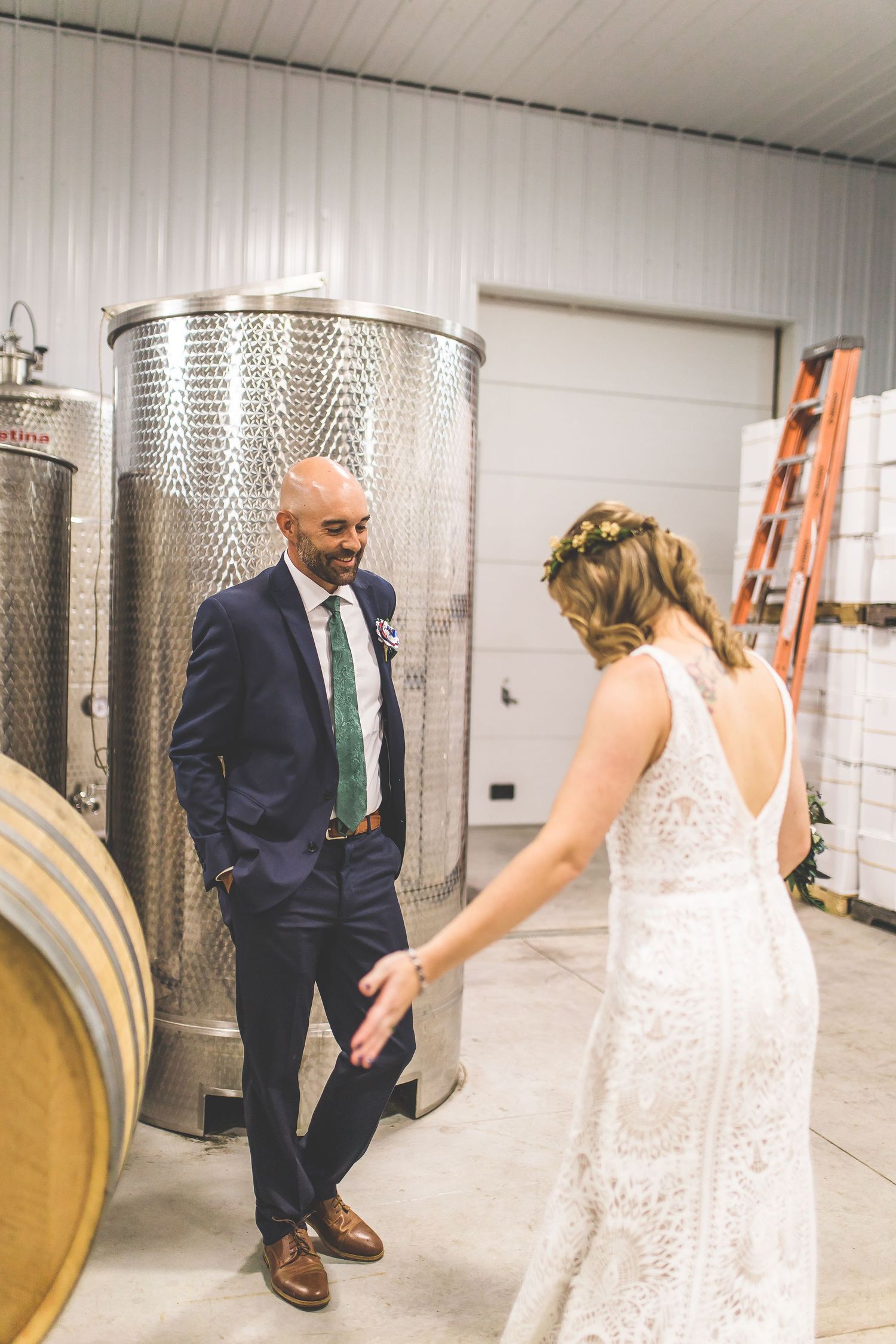 A couple shares a romantic moment among stainless steel wine tanks in a winery cellar.