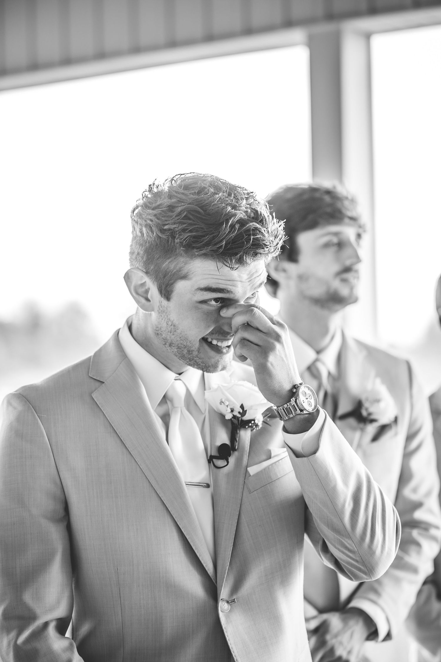 Emotional moment captured in black and white as groomsman wipes away tears during wedding ceremony.