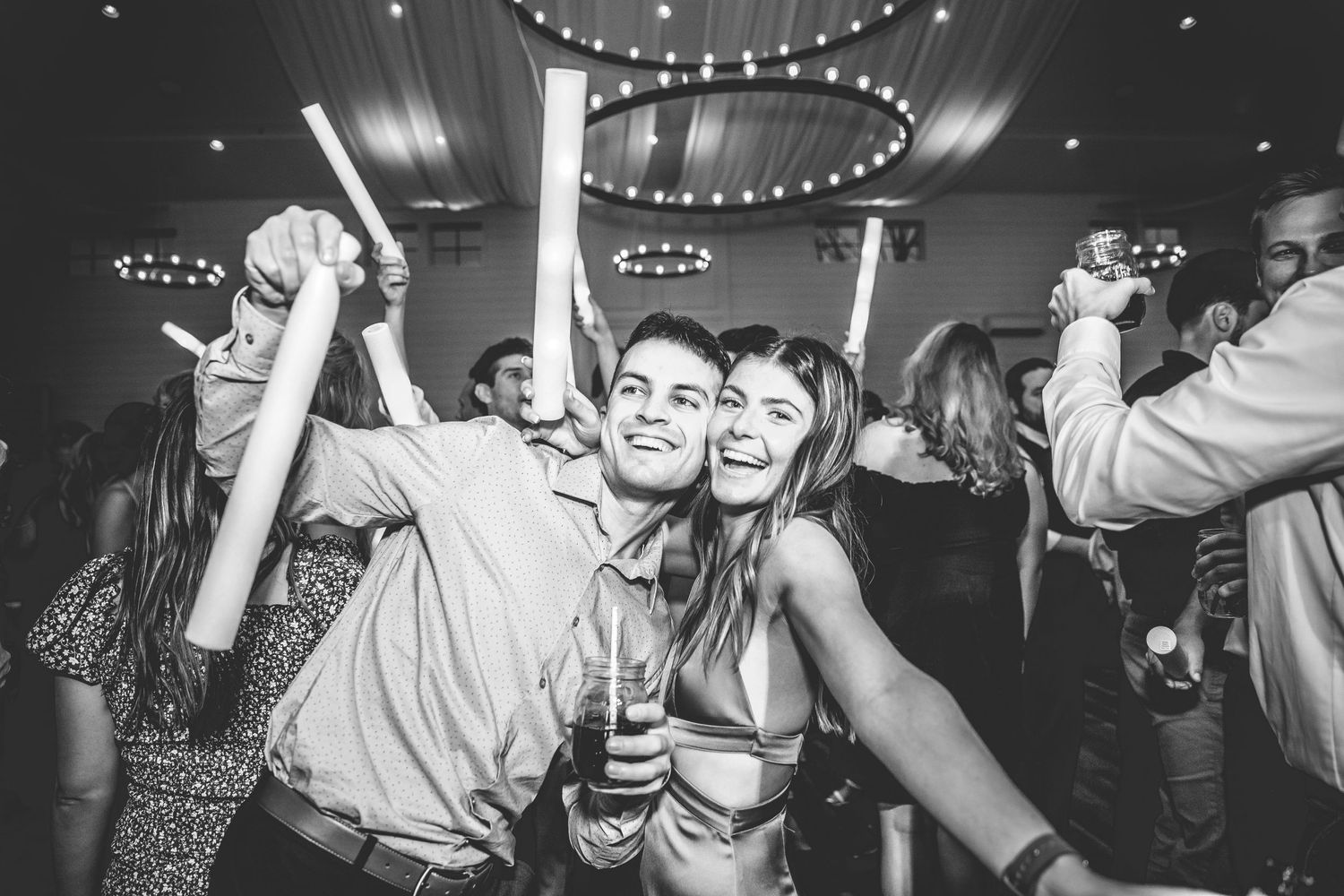 Black and white photo of party guests dancing and celebrating at a nighttime event.