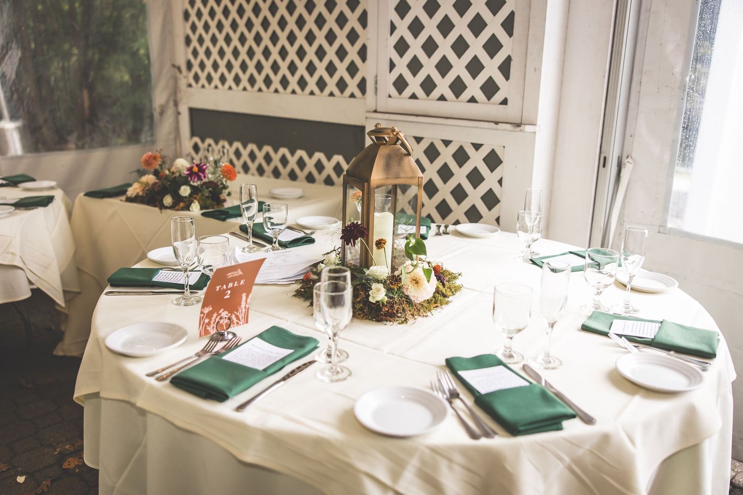 Wedding reception table settings with white linens and elegant place settings.