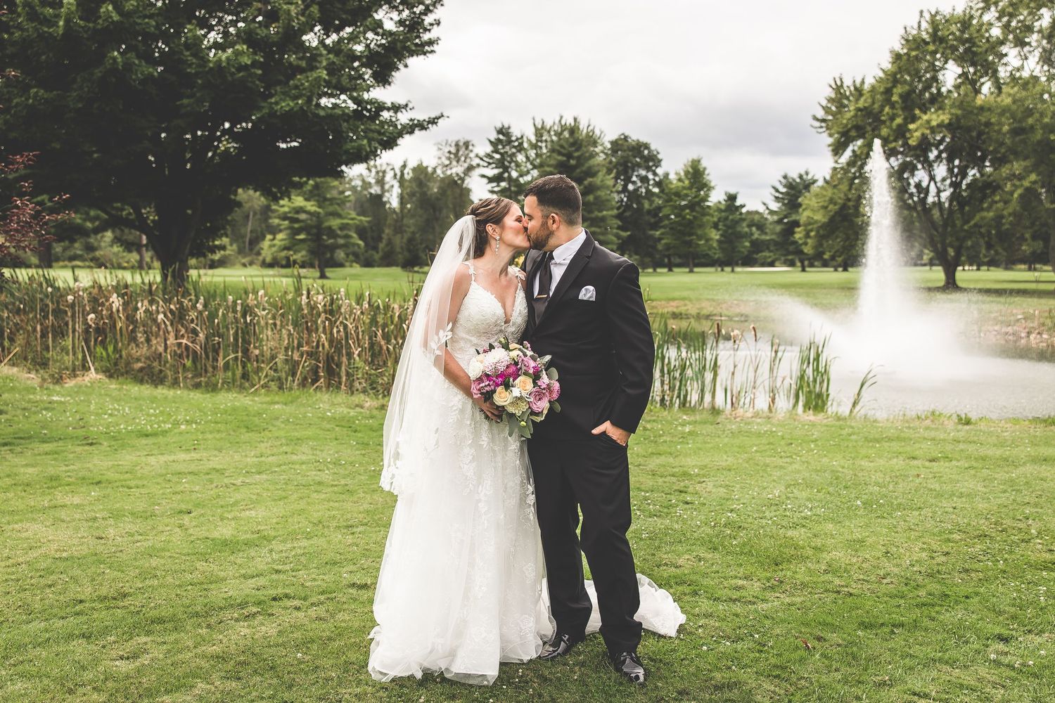 Wedding photography session on rolling green hills with a water feature in view.