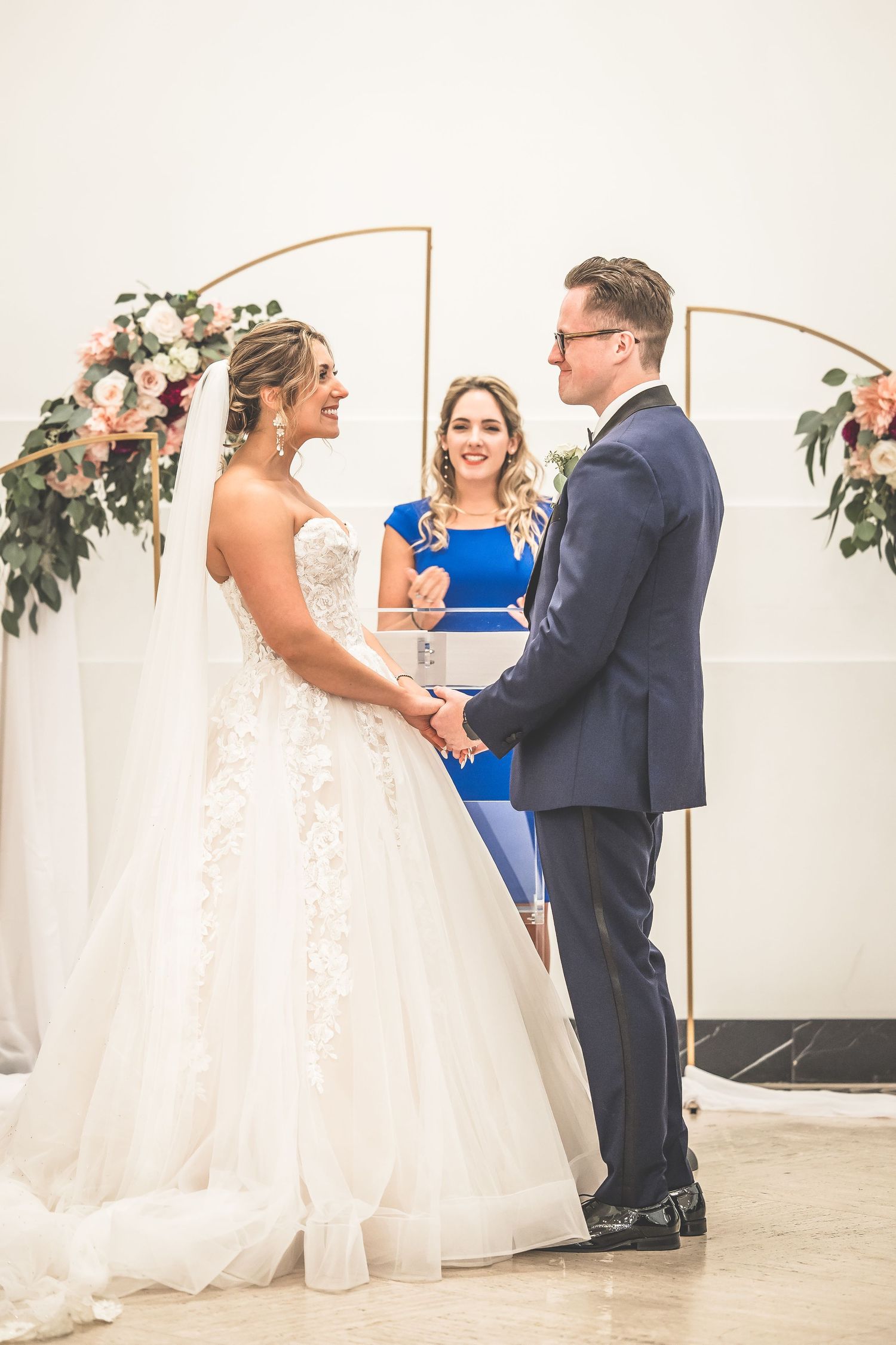 Wedding ceremony moments captured under decorative copper arch with floral accents.