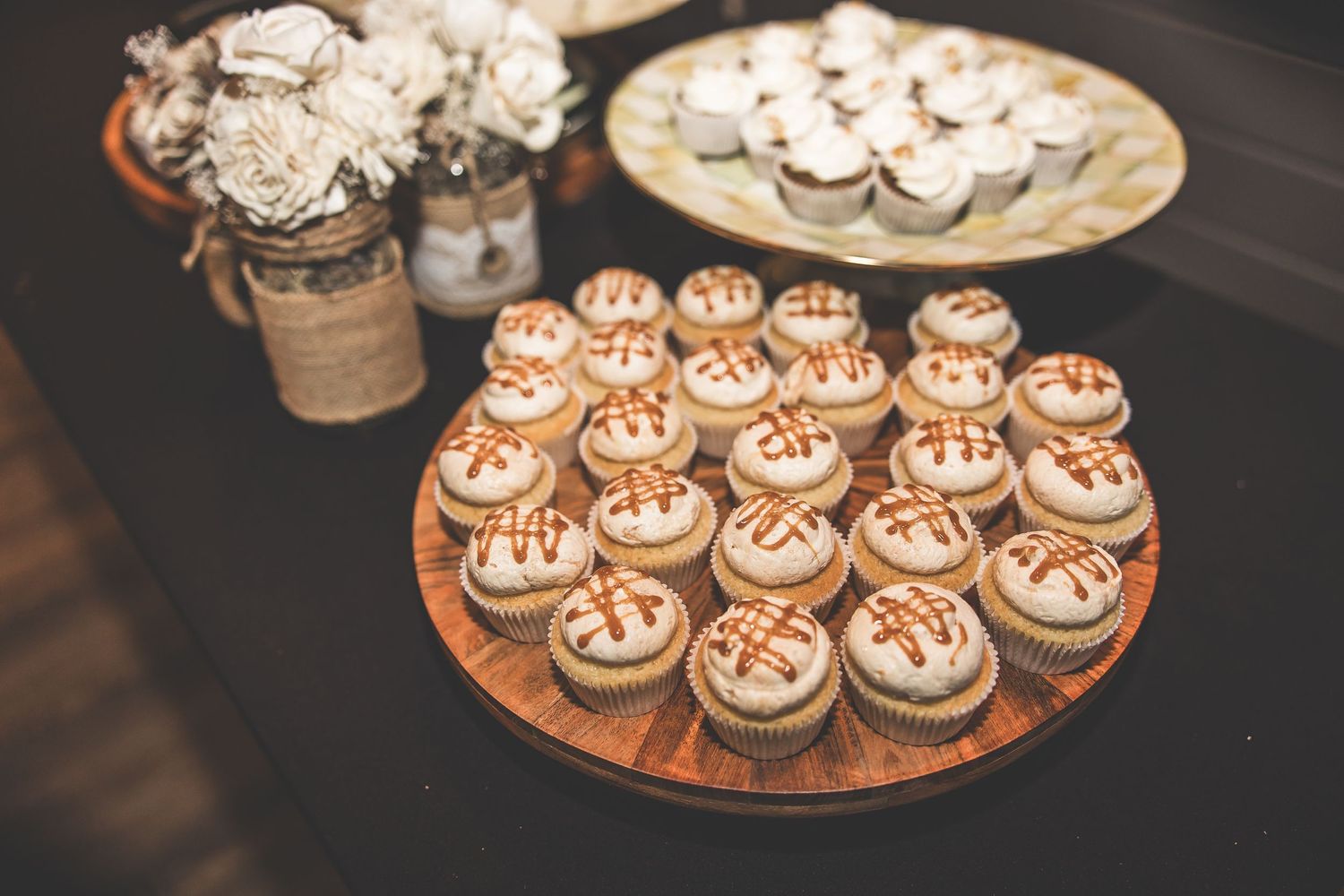 Elegant display of decorated cupcakes arranged on wooden serving platters.