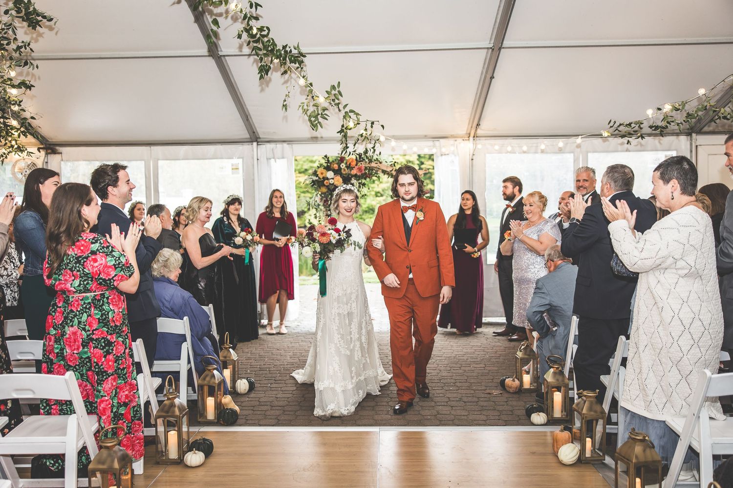 Wedding reception in tent venue with string lights and floral decor.