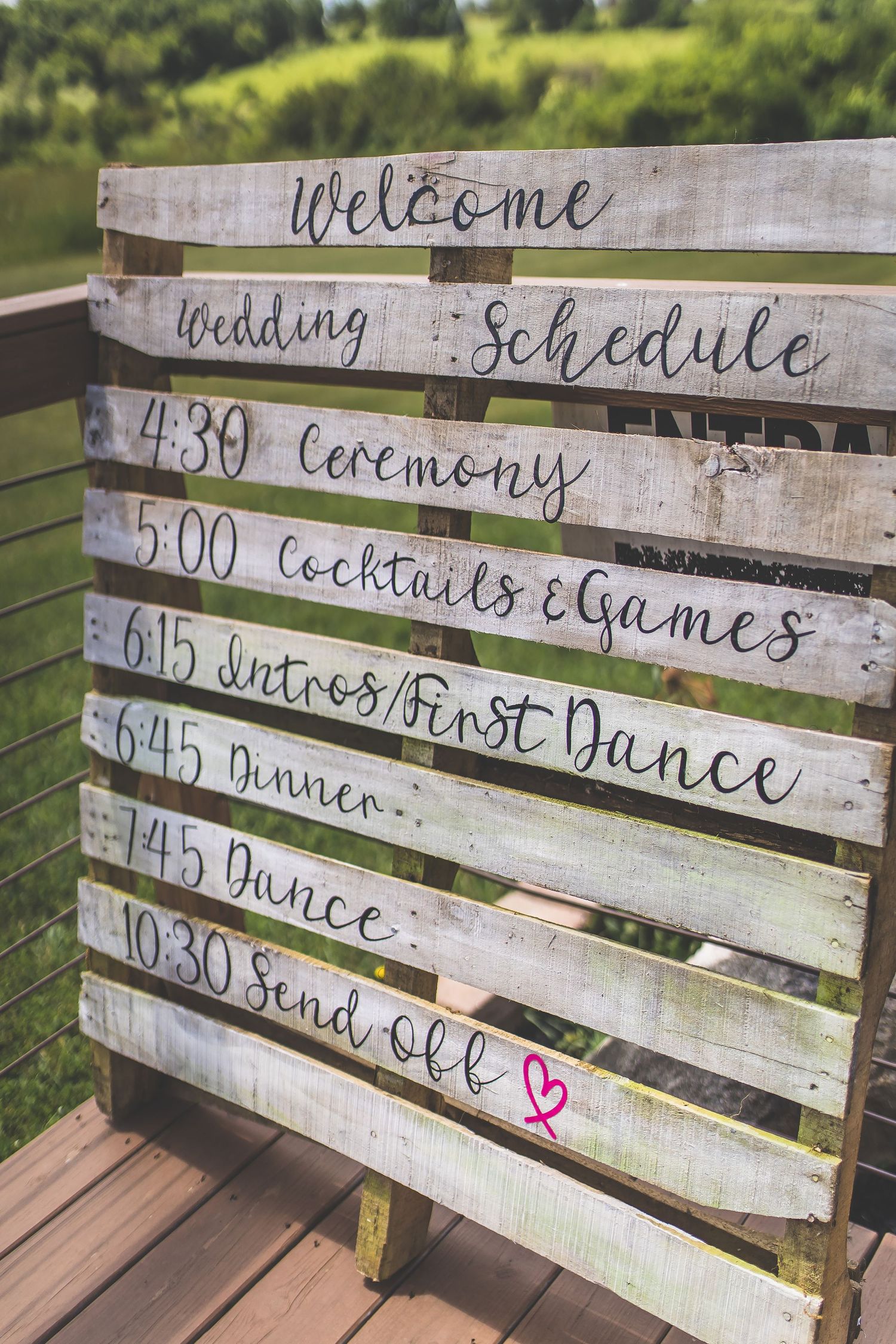 Rustic wooden pallet sign displaying wedding day timeline and schedule details.