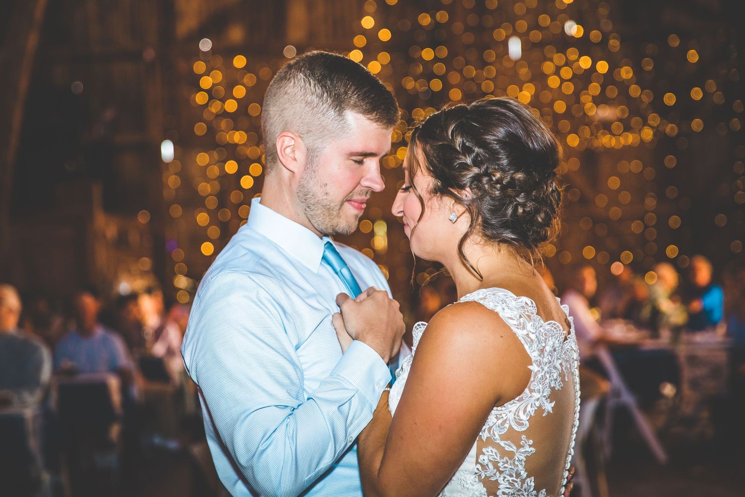 Romantic dance moments illuminated by warm bokeh lights at an evening reception.