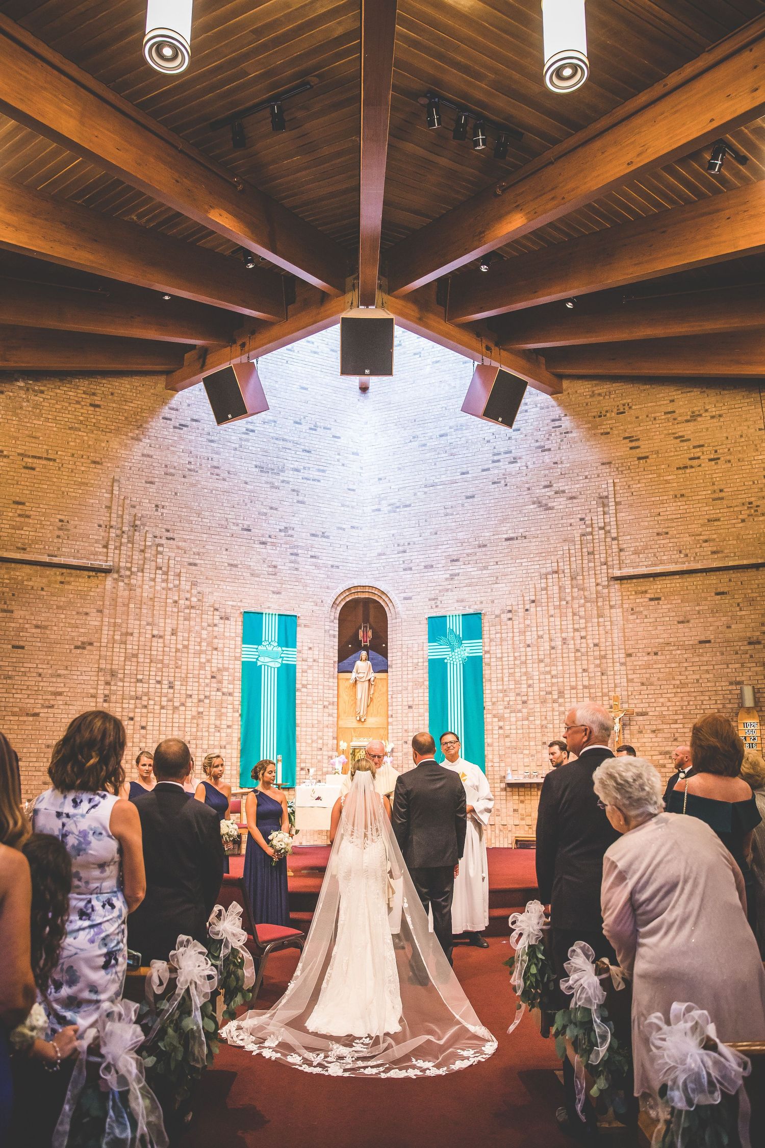 Panoramic view of a wedding ceremony in a brick chapel with turquoise accents.
