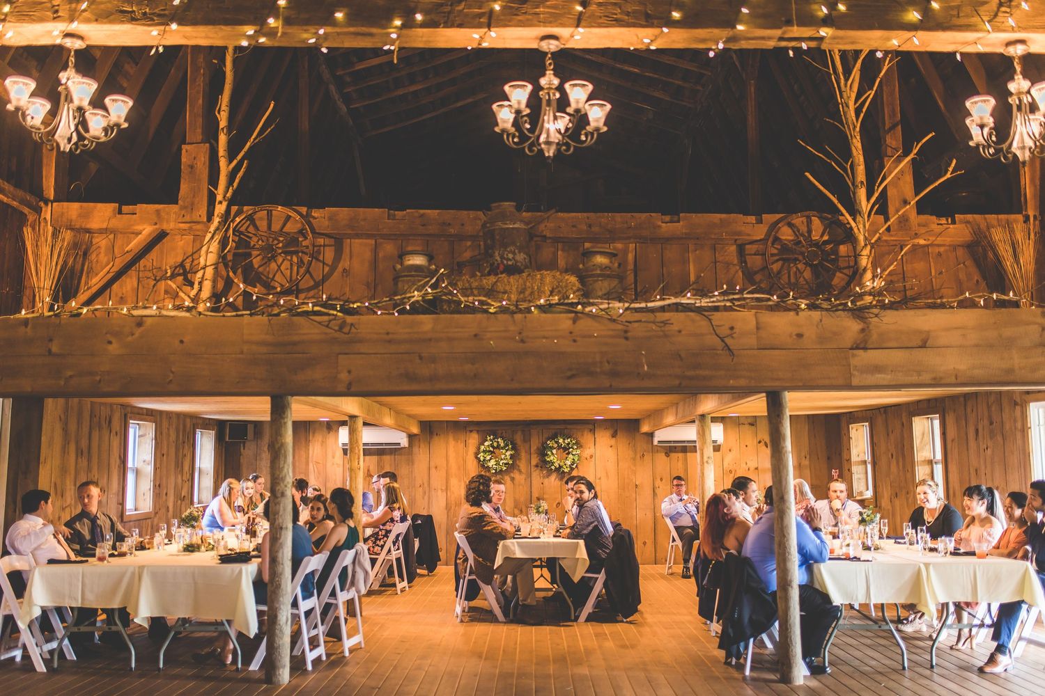 Large rustic barn reception venue with string lights and tables set for wedding celebration.
