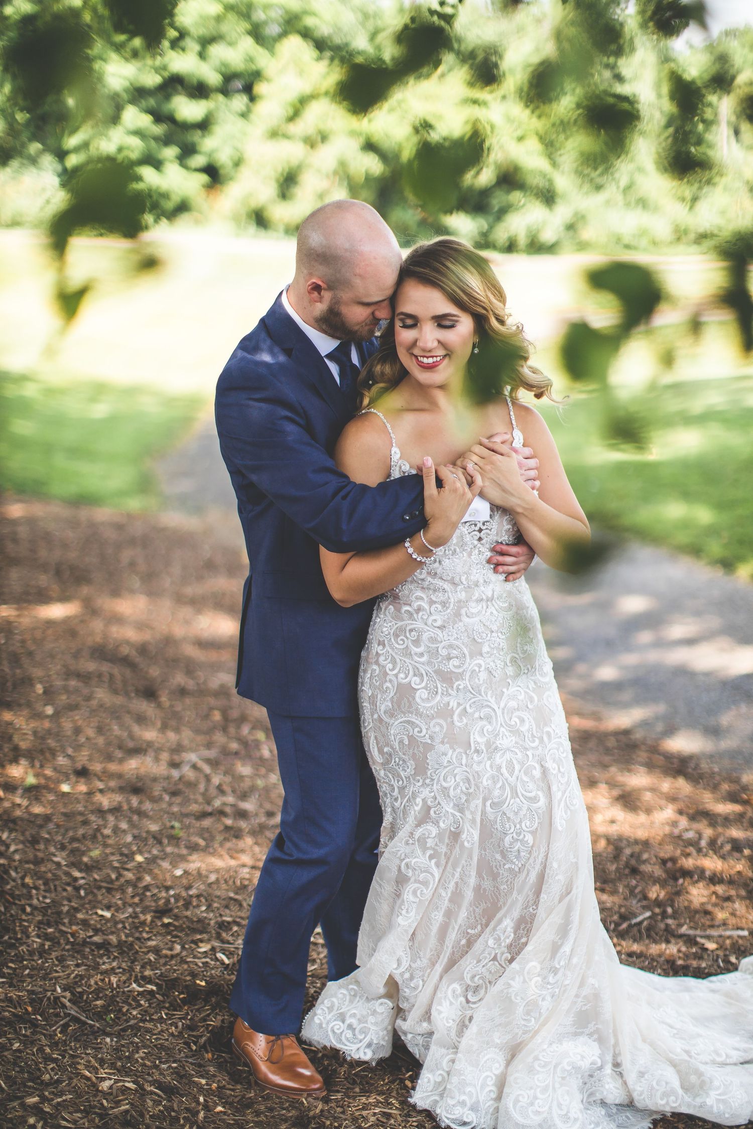 A romantic moment between newlyweds embracing outdoors in a garden setting.