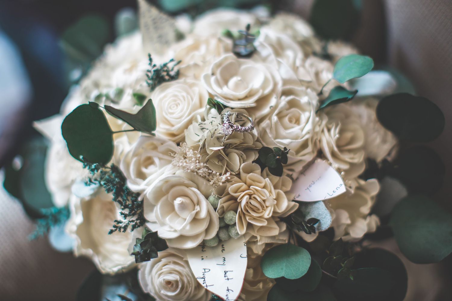Close-up details of delicate white and cream paper roses with eucalyptus leaves.