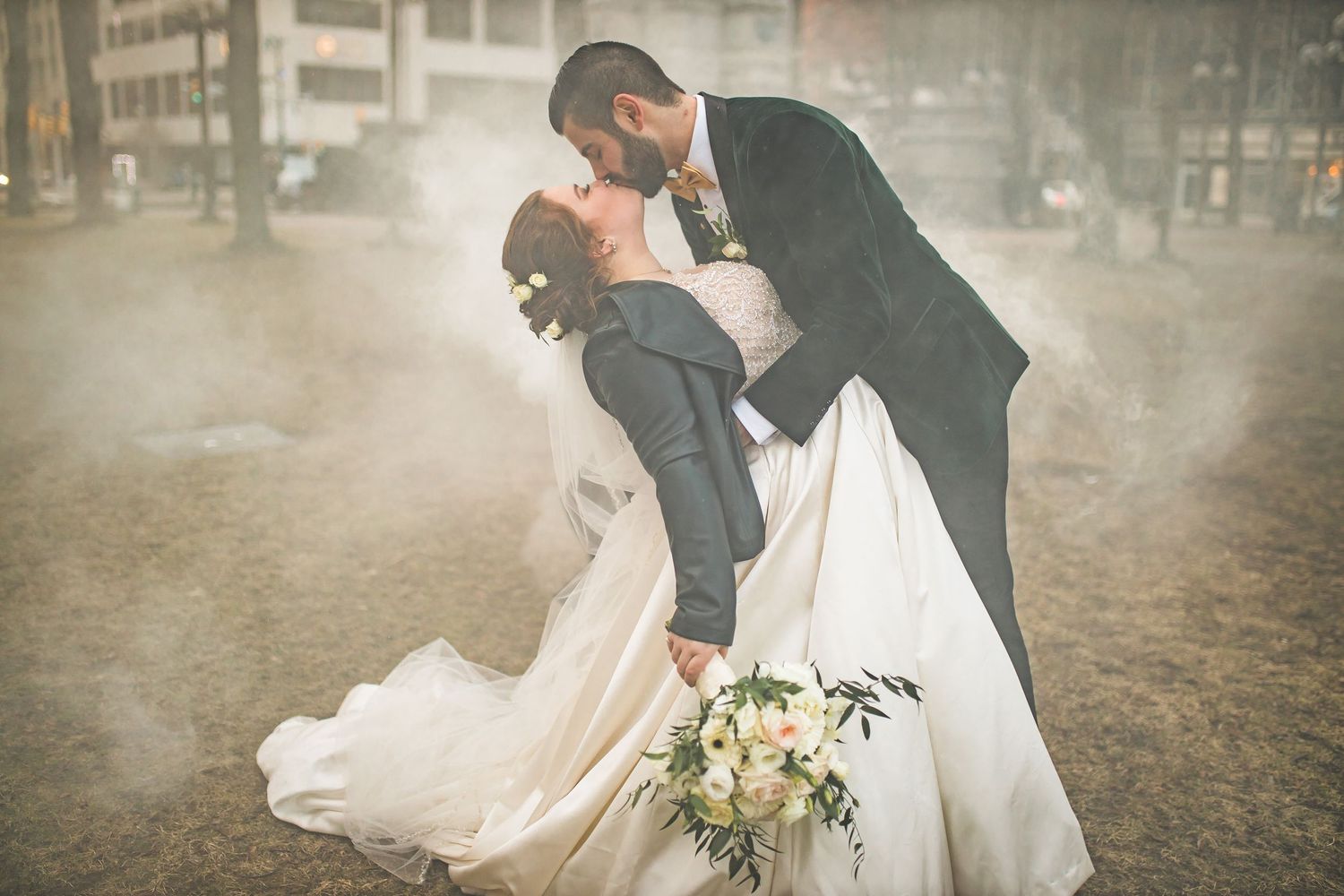 A romantic wedding photo captured in dreamy fog with a white bouquet and flowing dress.