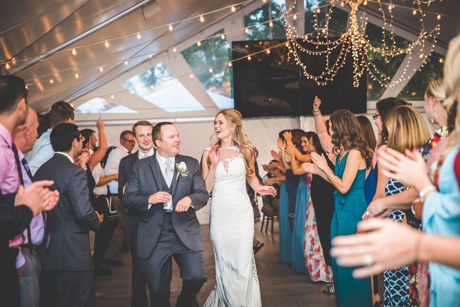 Wedding reception venue with string lights and guests dancing under romantic lighting.