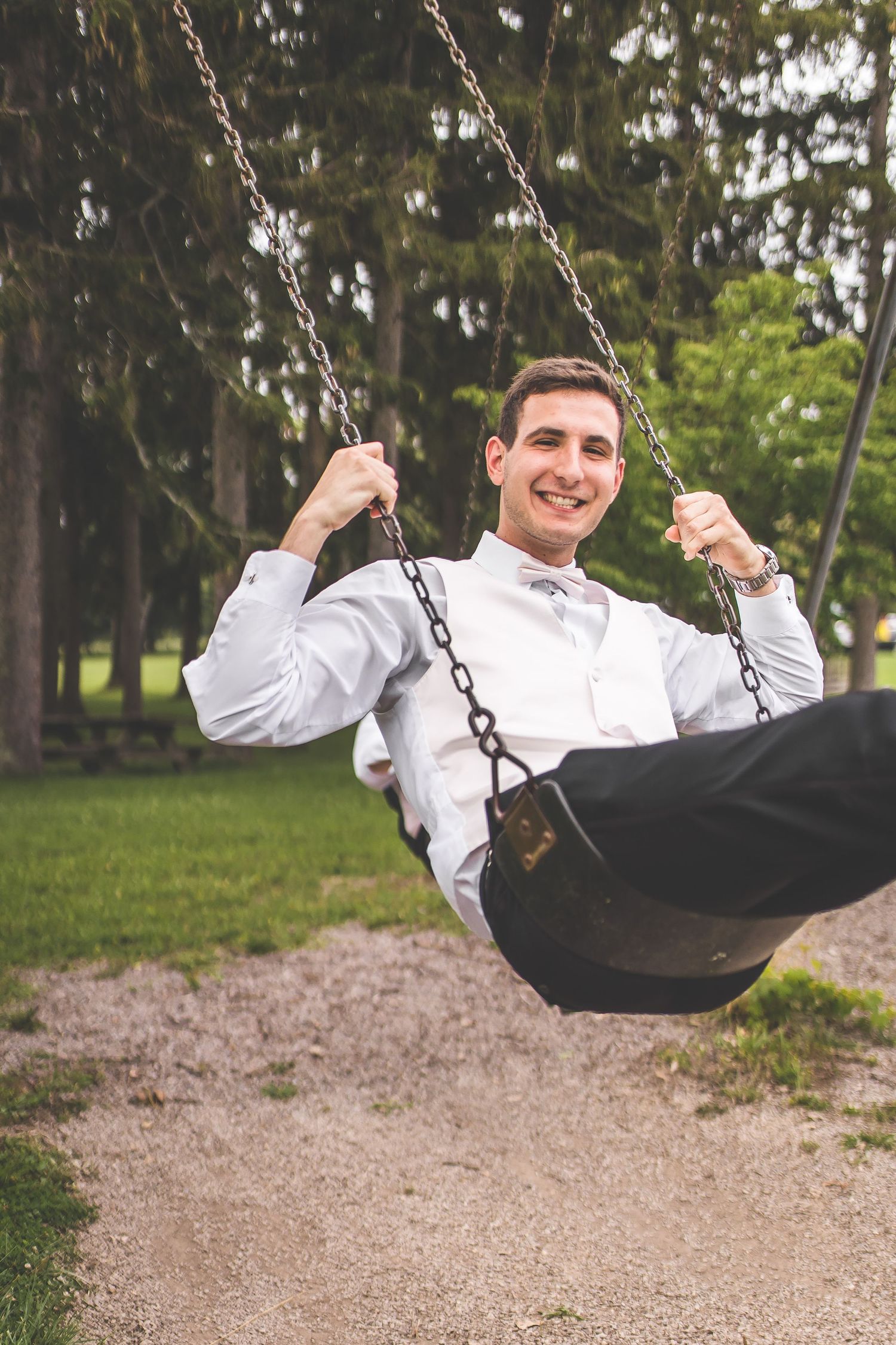 Playful sequence of someone swinging on a playground swing in formal attire.