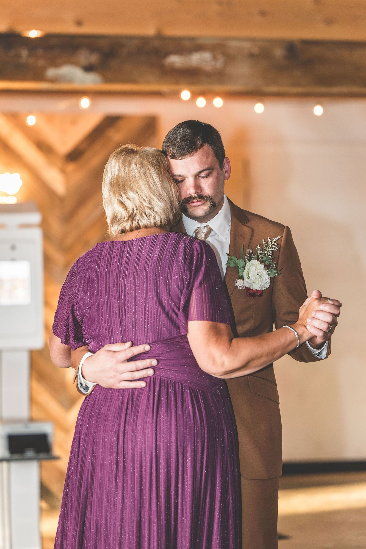 Wedding party members share emotional dances in purple dresses and brown suits.
