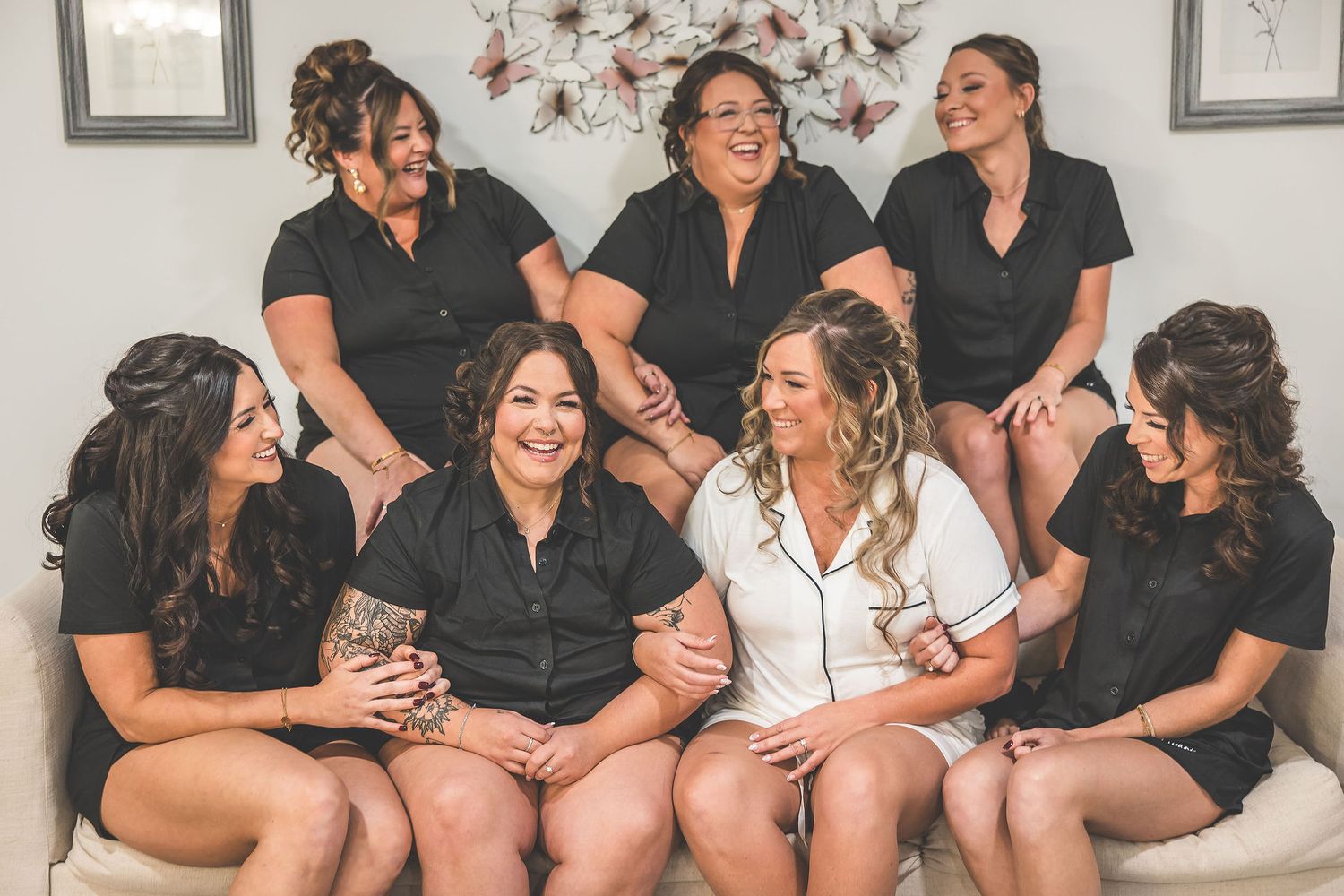 Wedding party members in matching black outfits sitting together and laughing.