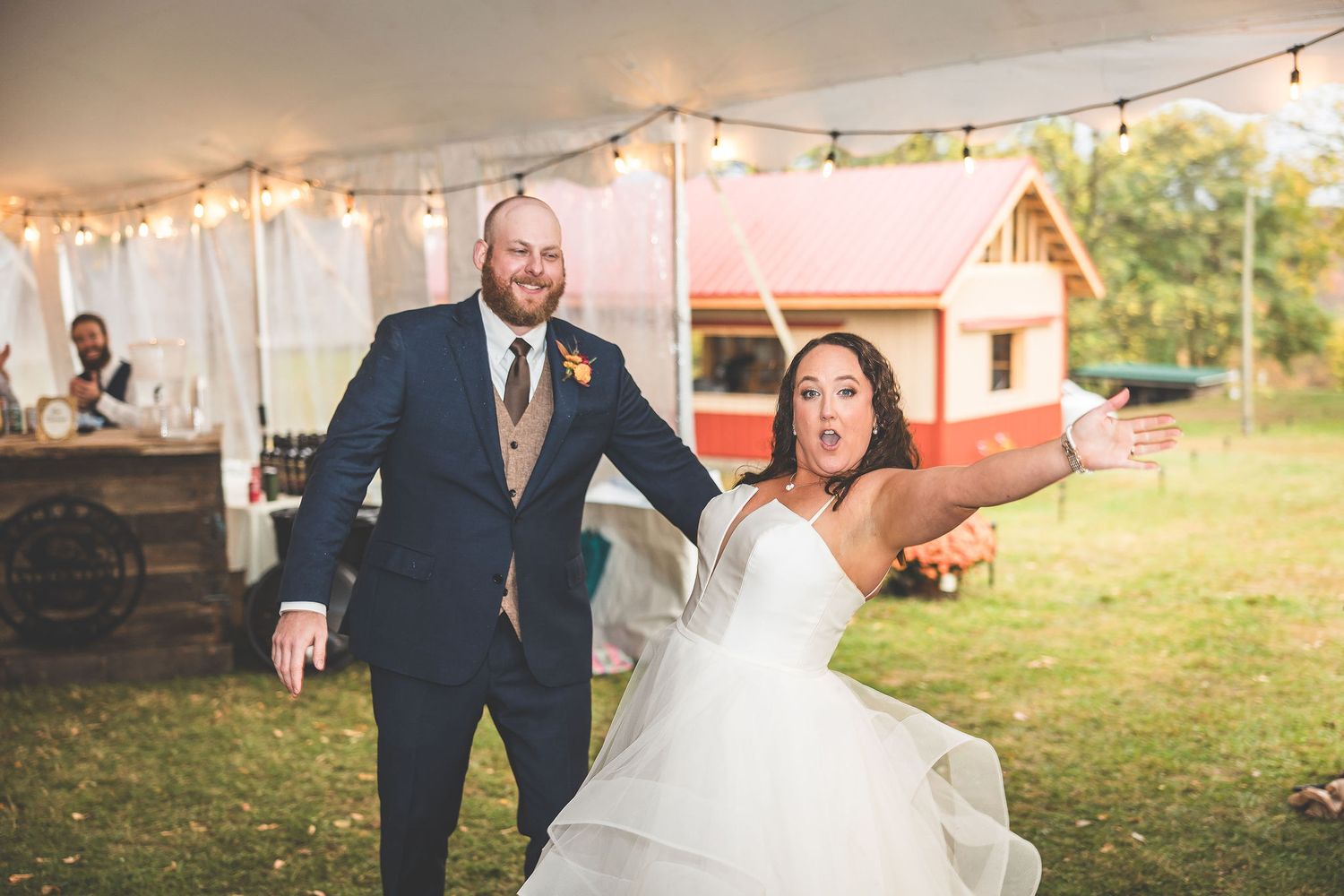 Wedding celebration inside decorated tent with string lights and white fabric draping.