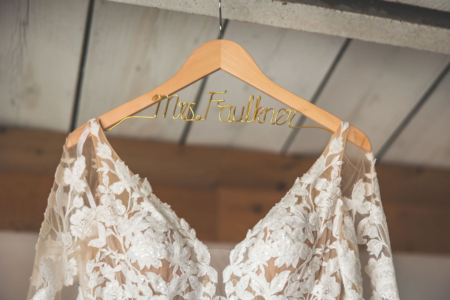 Delicate lace wedding dress hanging on display.