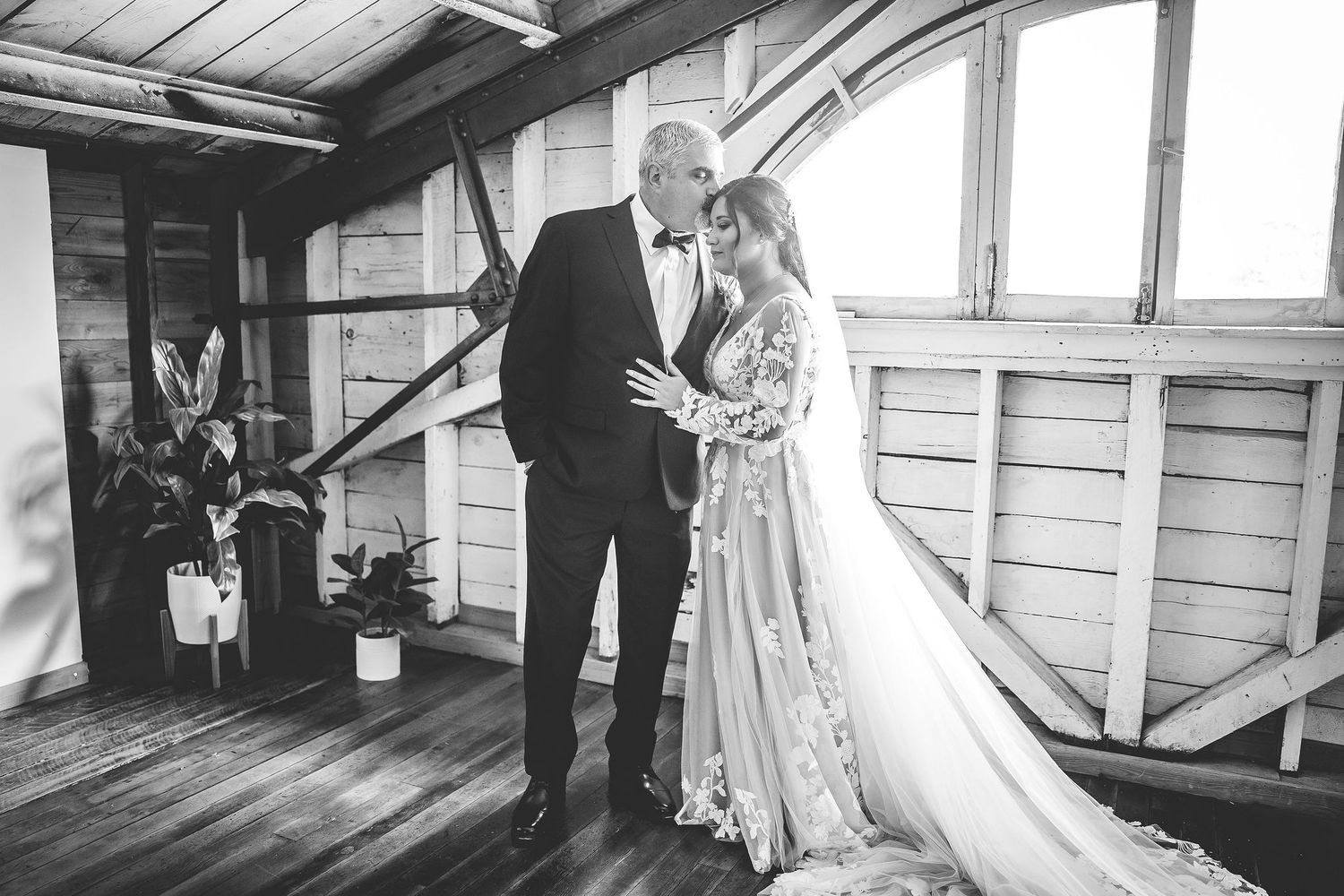 Wedding party members interact in a bright, rustic room with wooden architecture.